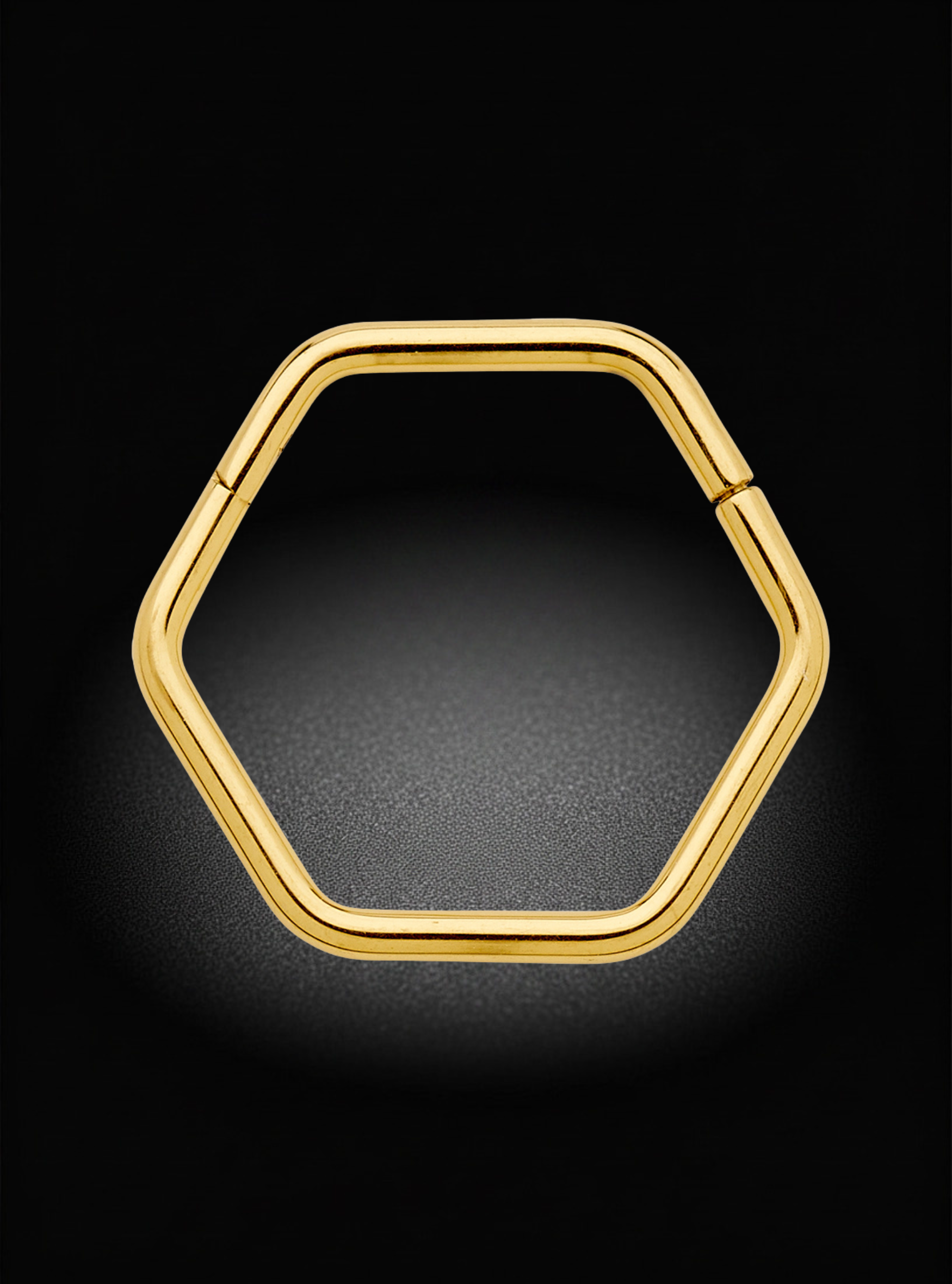 A gold hexagonal hoop earring shown from the front on a black background with a soft glow.