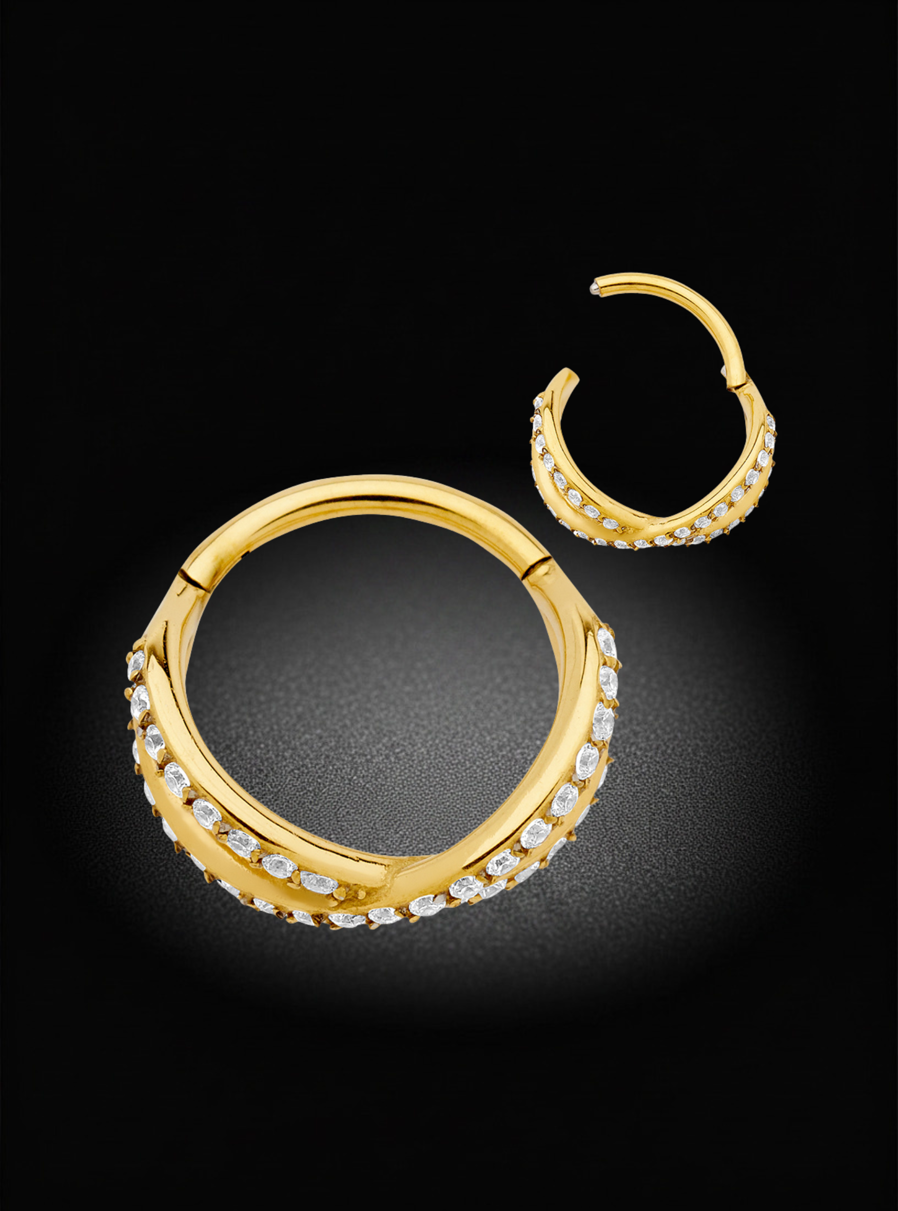 A pair of gold hoop earrings with rows of clear pavé stones, displayed on a dark black background.