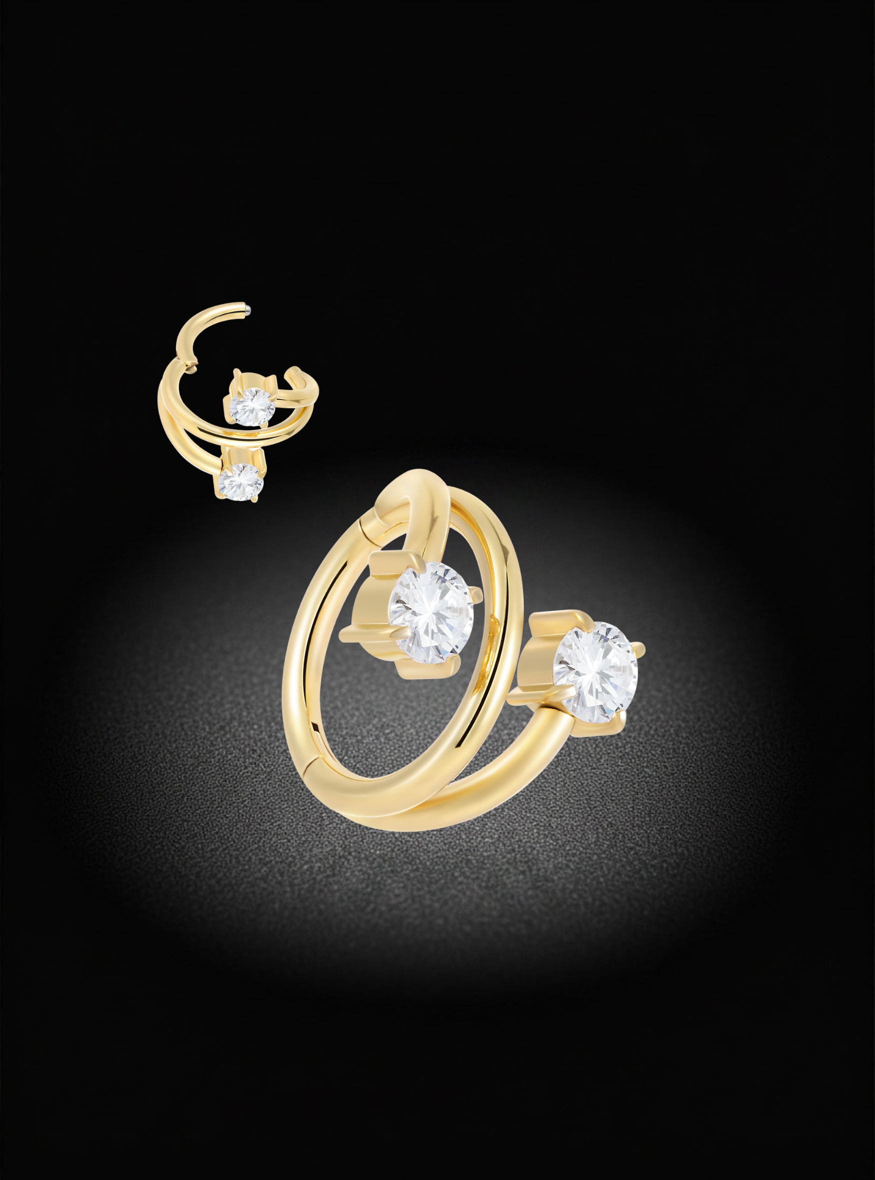 A pair of gold hoop earrings with clear round-cut gemstones, displayed against a black background with a soft spotlight effect.