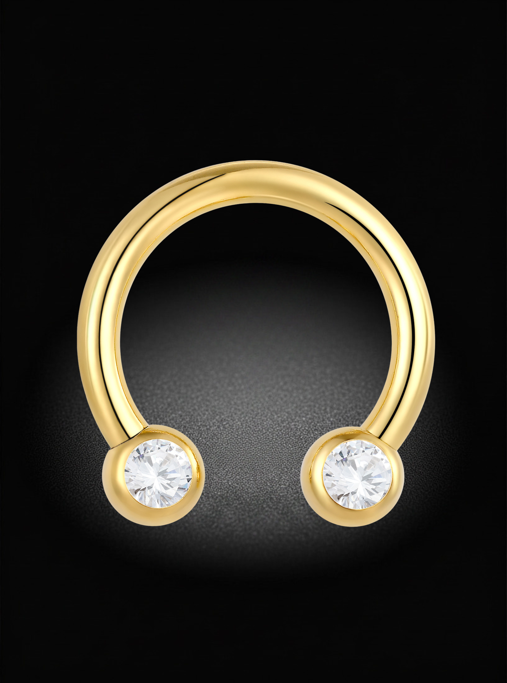 A gold curved barbell-style ring with two round bezel-set clear gemstones, shown on a black background.