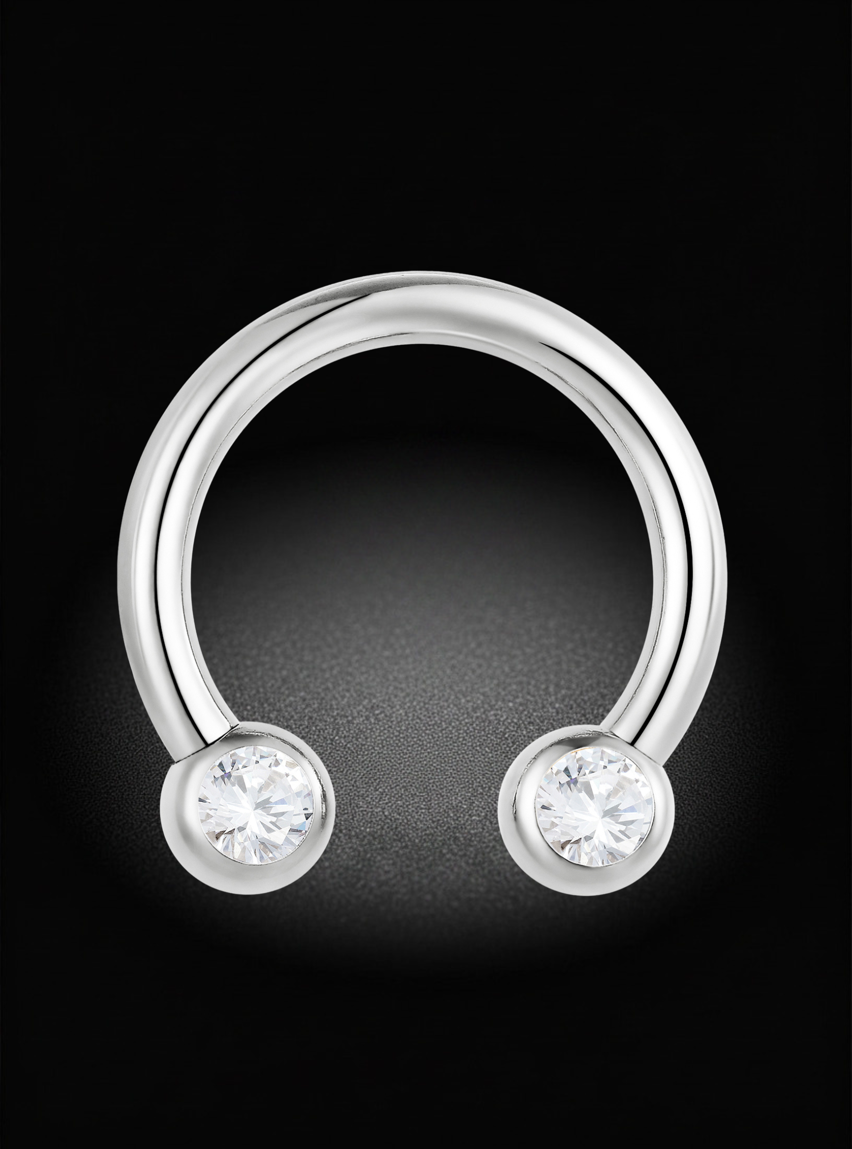 A silver-toned curved barbell stud piercing ring with two round bezel-set clear gemstones on a black background.