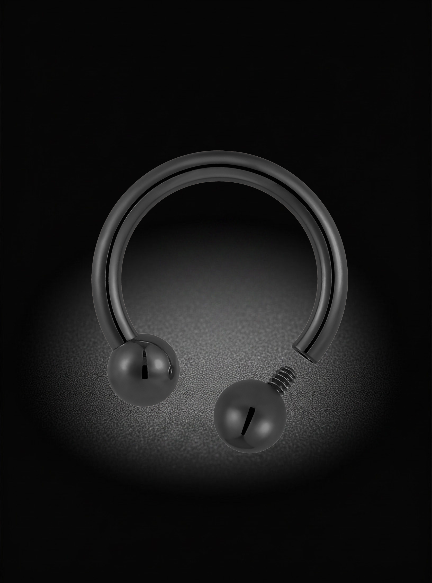 A black metal curved barbell piercing stud with spherical ball ends, shown on a dark textured background with a spotlight effect.