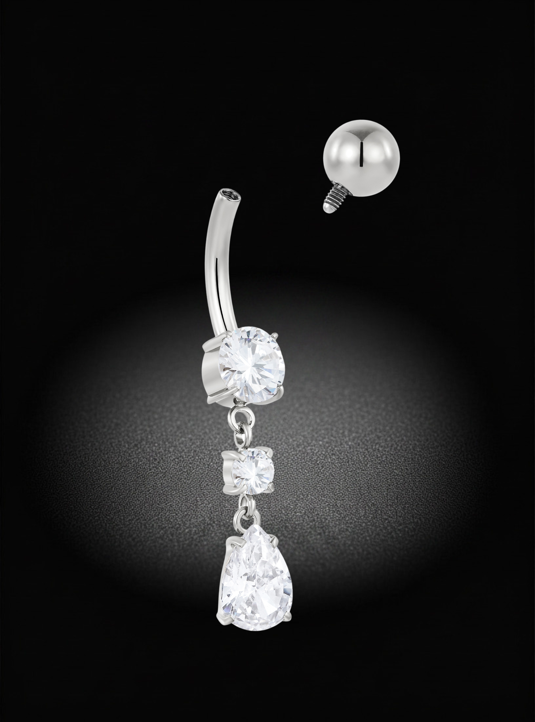 A silver-toned belly button ring with three dangling clear gemstones, shown against a black background with a separate ball back visible in the upper right.