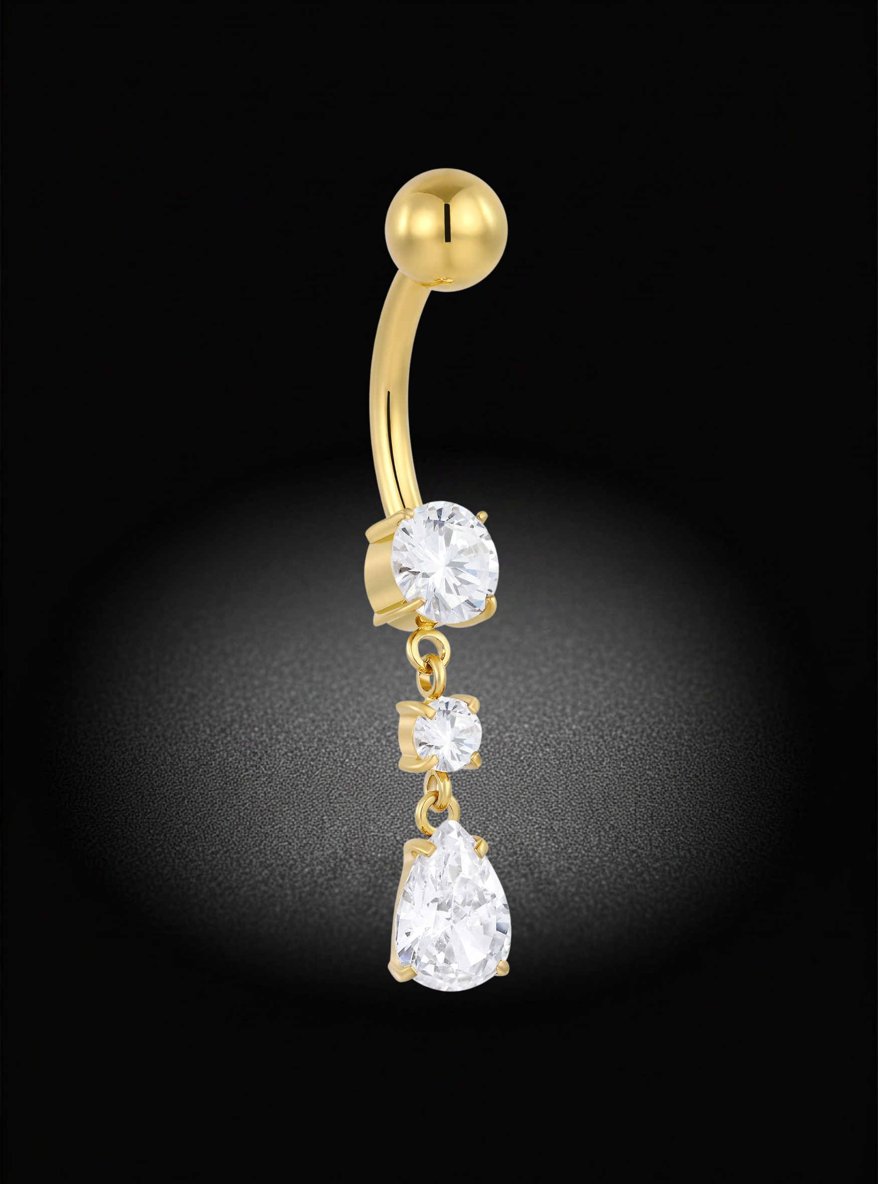 A gold curved barbell belly button ring with three dangling clear gemstones of graduated sizes, set against a black background with a spotlight effect.
