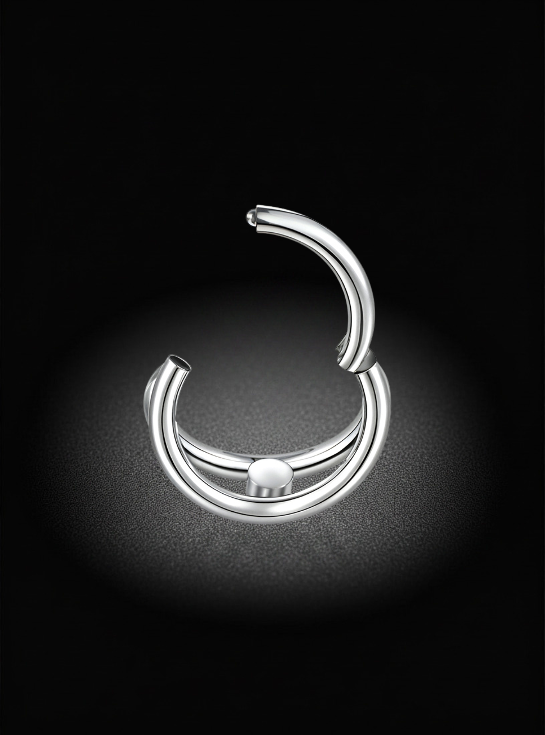 A polished silver-toned curved hoop earring with a small central bead detail, displayed on a dark textured background with a spotlight effect.