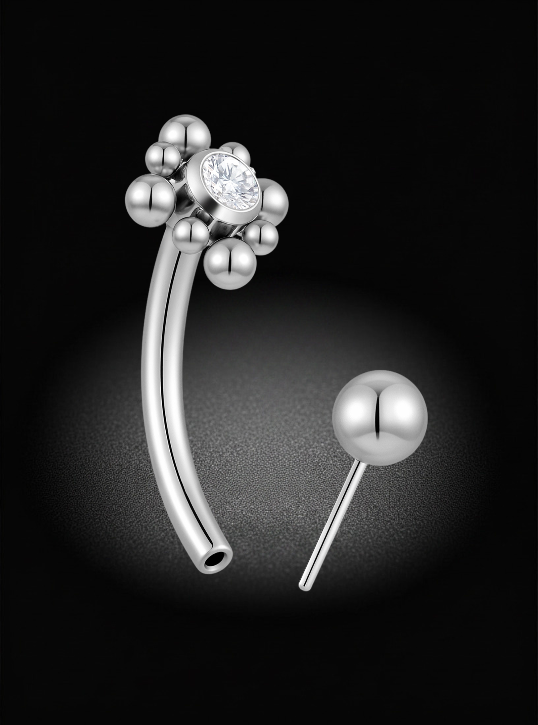 Silver titanium curved eyebrow barbell with a flower-like cluster of beads and a central clear gemstone, shown alongside a separate round ball stud on a black background.