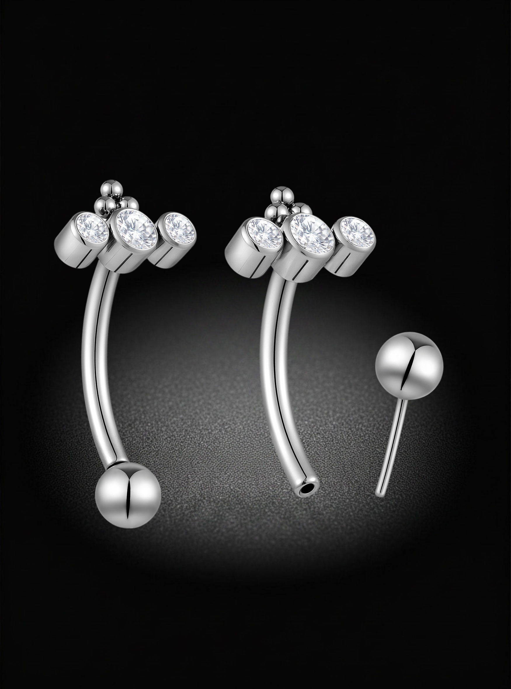 Silver curved eyebrow barbells piercings with three small clear gemstone clusters at the top and a ball-shaped end, shown on a black background with one piece displayed separately.