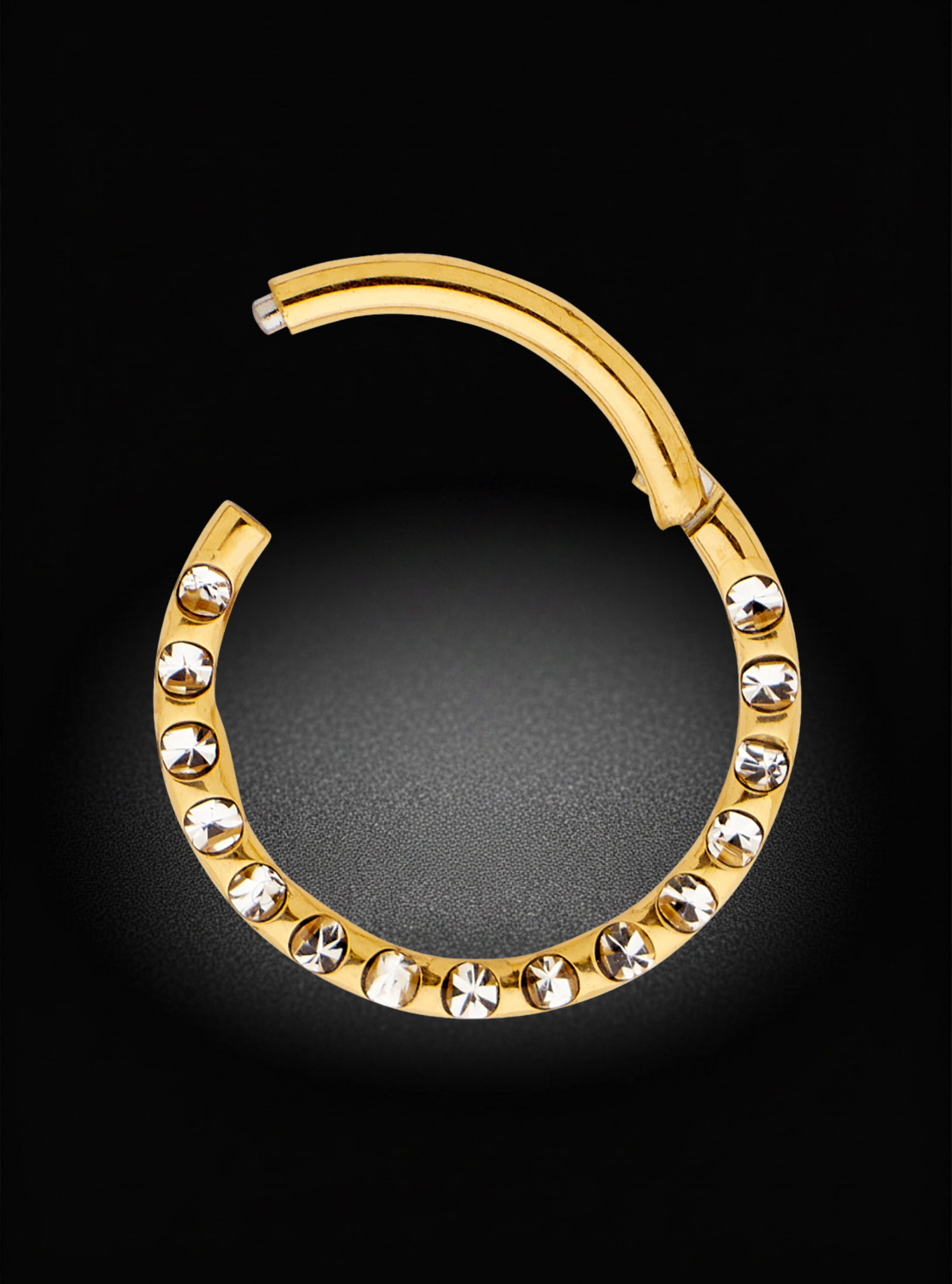 A gold-colored curved hoop earring embellished with a row of clear rhinestones, displayed against a solid black background.