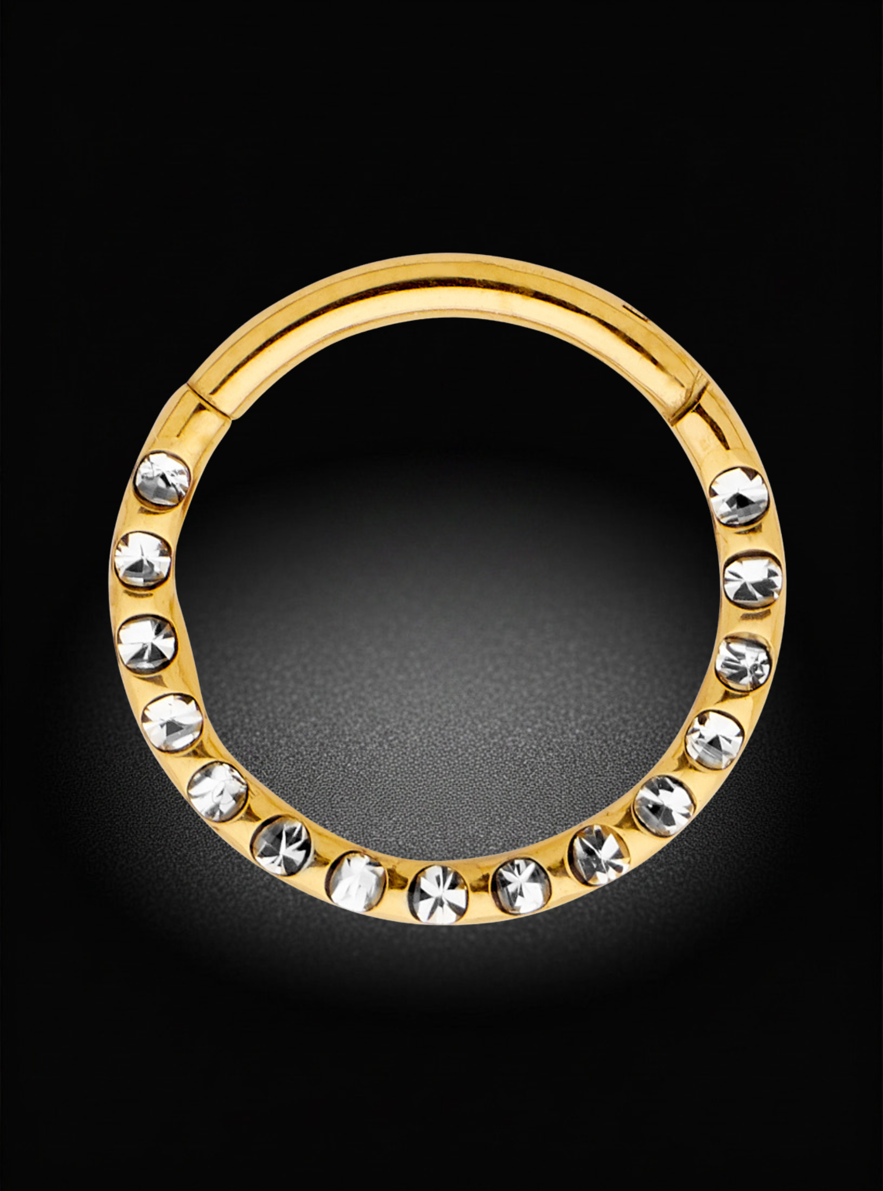 A gold-plated circular hoop ring decorated with a row of clear rhinestones, set against a solid black background.