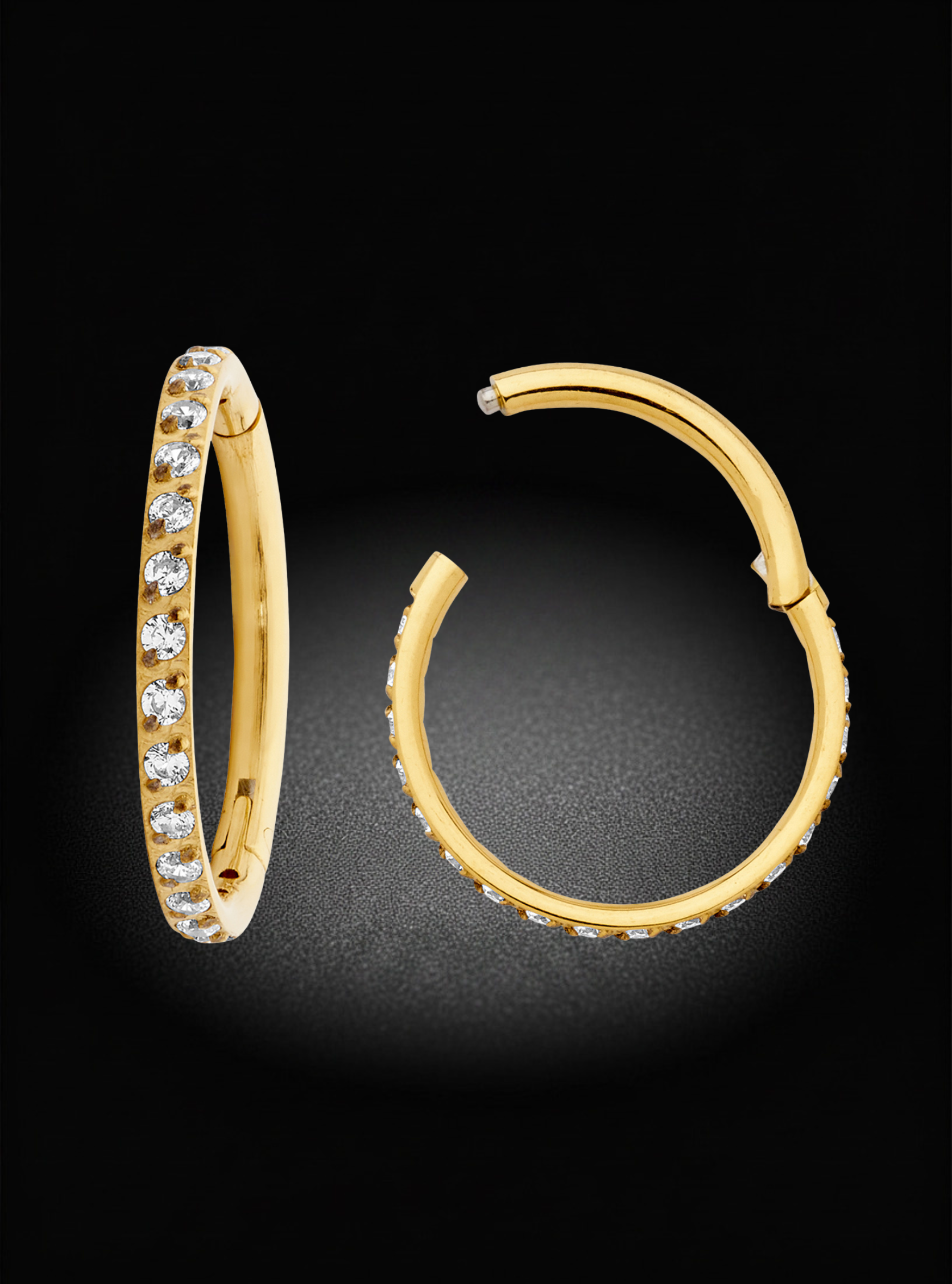 A pair of gold hoop earrings with a row of clear stones on one earring, shown on a black background. One earring is oriented vertically to show the front with the stones, and the other is oriented horizontally to show the side profile.