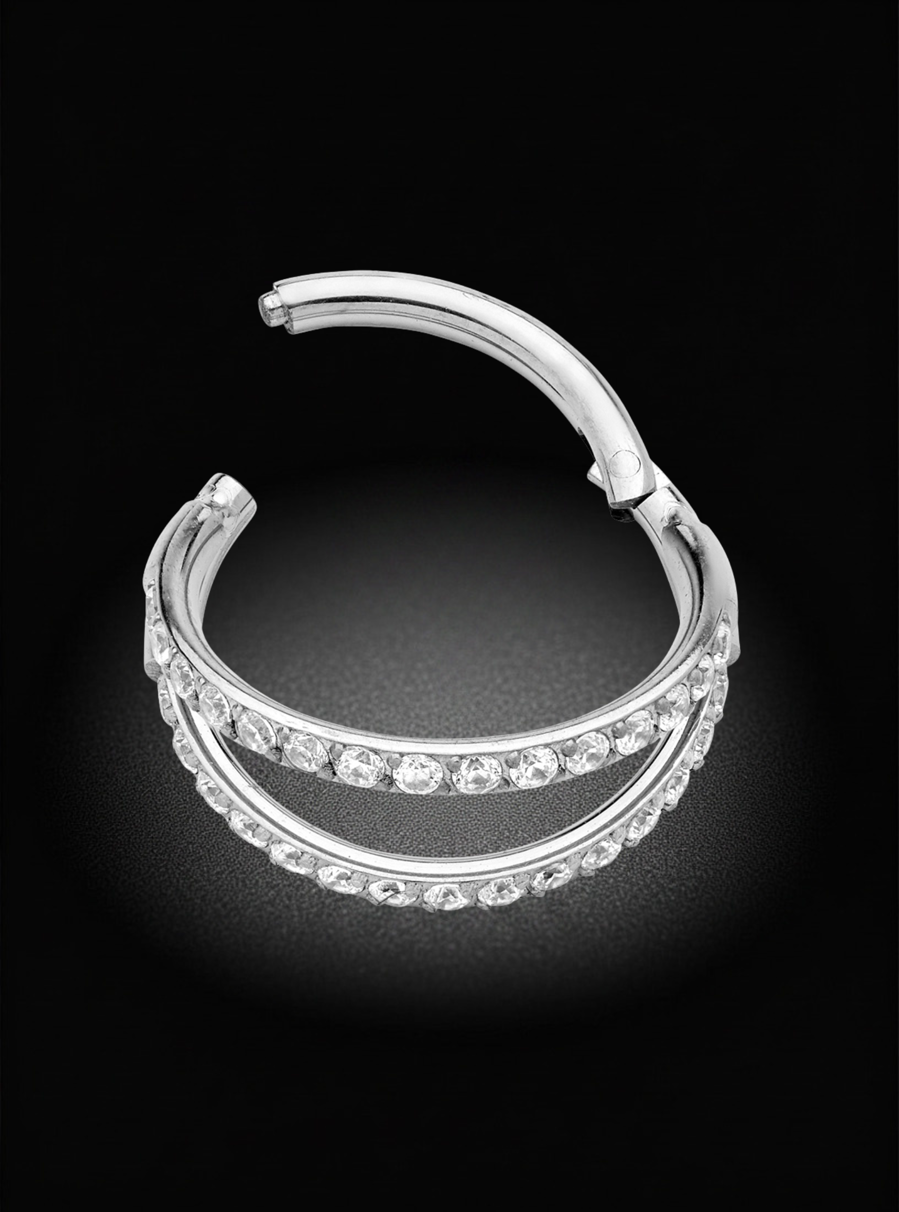 A silver-toned titanium hinged segment earring with three parallel rows of clear pavé-set stones, photographed on a black background.
