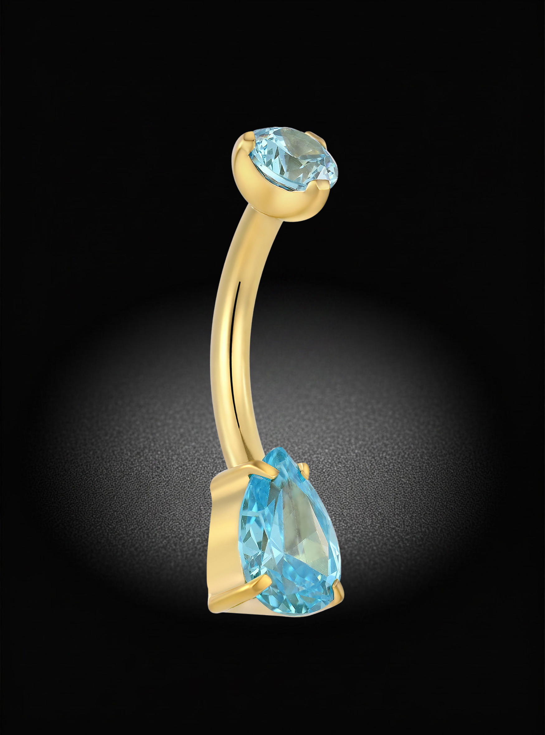 A curved gold body jewelry ring featuring a large pear-cut light blue gemstone and a smaller round light blue gemstone at the top, set against a dark background with a spotlight effect.