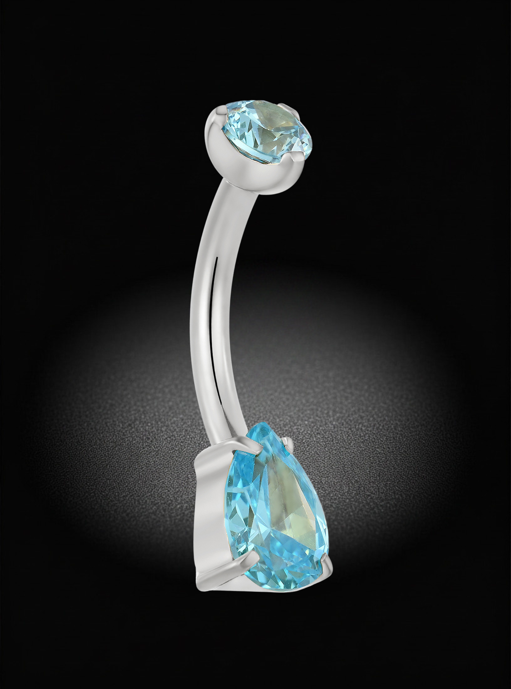 A curved barbell belly button ring featuring a large light blue teardrop gemstone and a smaller light blue oval gemstone in a silver-toned setting, shown against a black background with a spotlight effect.