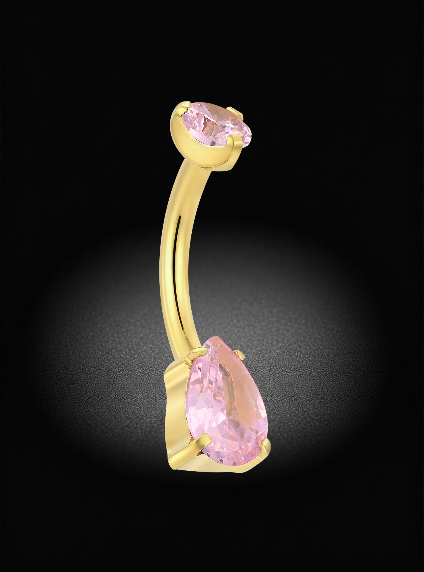 A curved barbell belly button ring in yellow gold, featuring a large pear-cut light pink gemstone on the bottom and a smaller oval light pink gemstone on the top, set against a dark background with a spotlight effect.