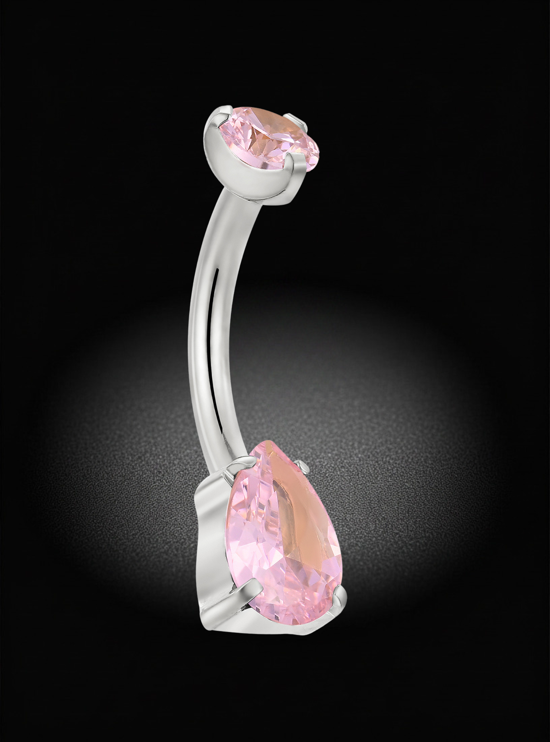A curved barbell belly button ring featuring a large faceted pink teardrop gemstone and a smaller oval pink gemstone, set in a polished silver-colored metal, shown against a dark black background with a soft spotlight effect.
