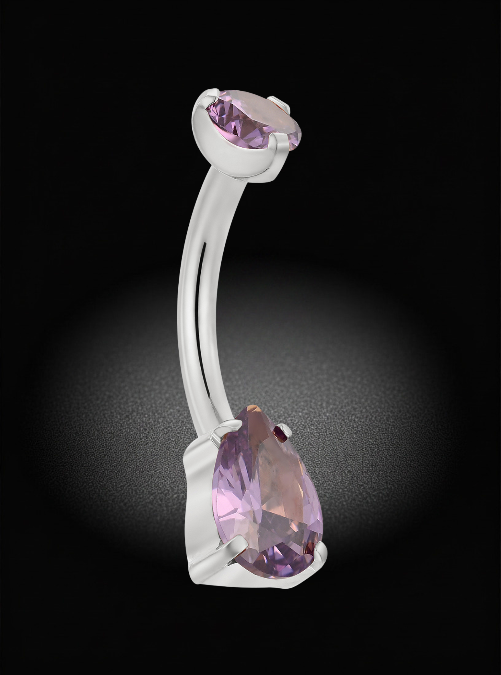 A curved barbell belly button ring with a large faceted lavender-purple teardrop gemstone and a smaller matching stone at the top, set in a polished silver-tone metal, shown against a dark black background with a soft spotlight effect.