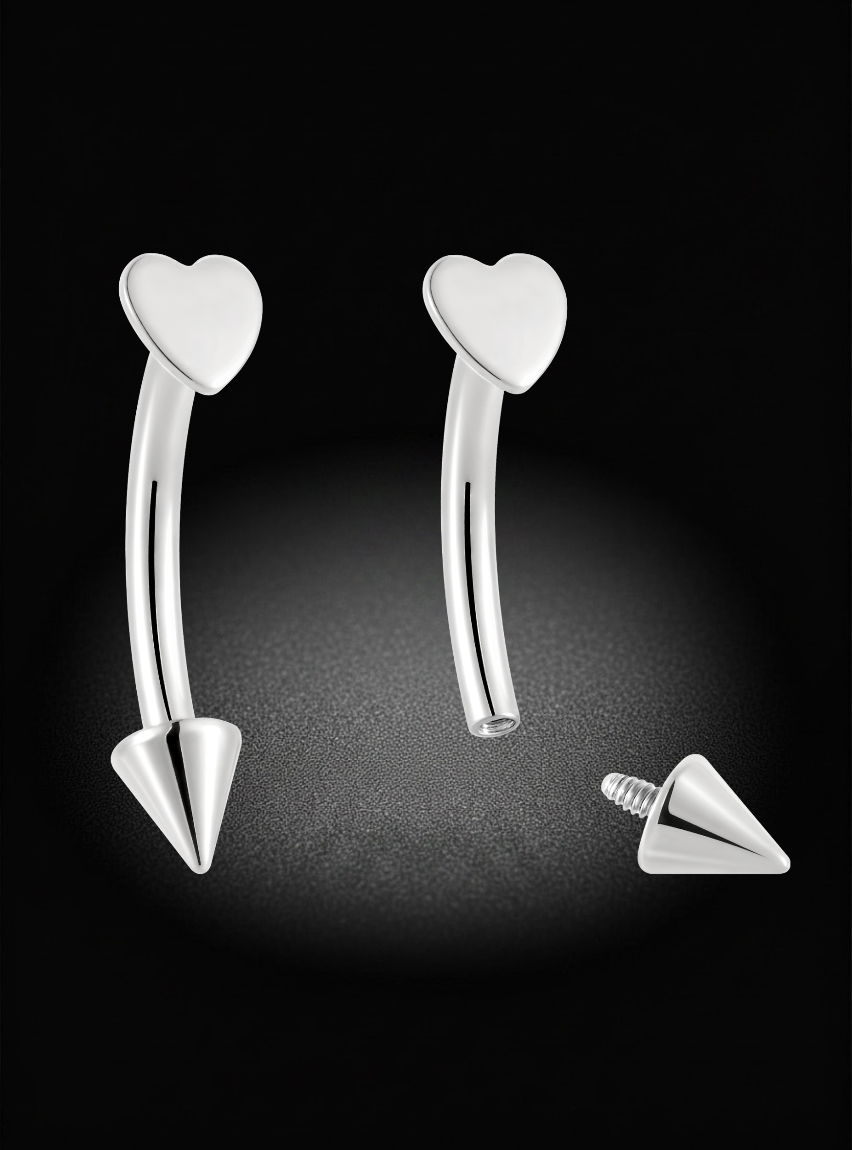 Silver curved barbell labret piercing studs with a heart-shaped top and a pointed bottom, shown on a black background with one stud assembled and the other showing the screw-back end.