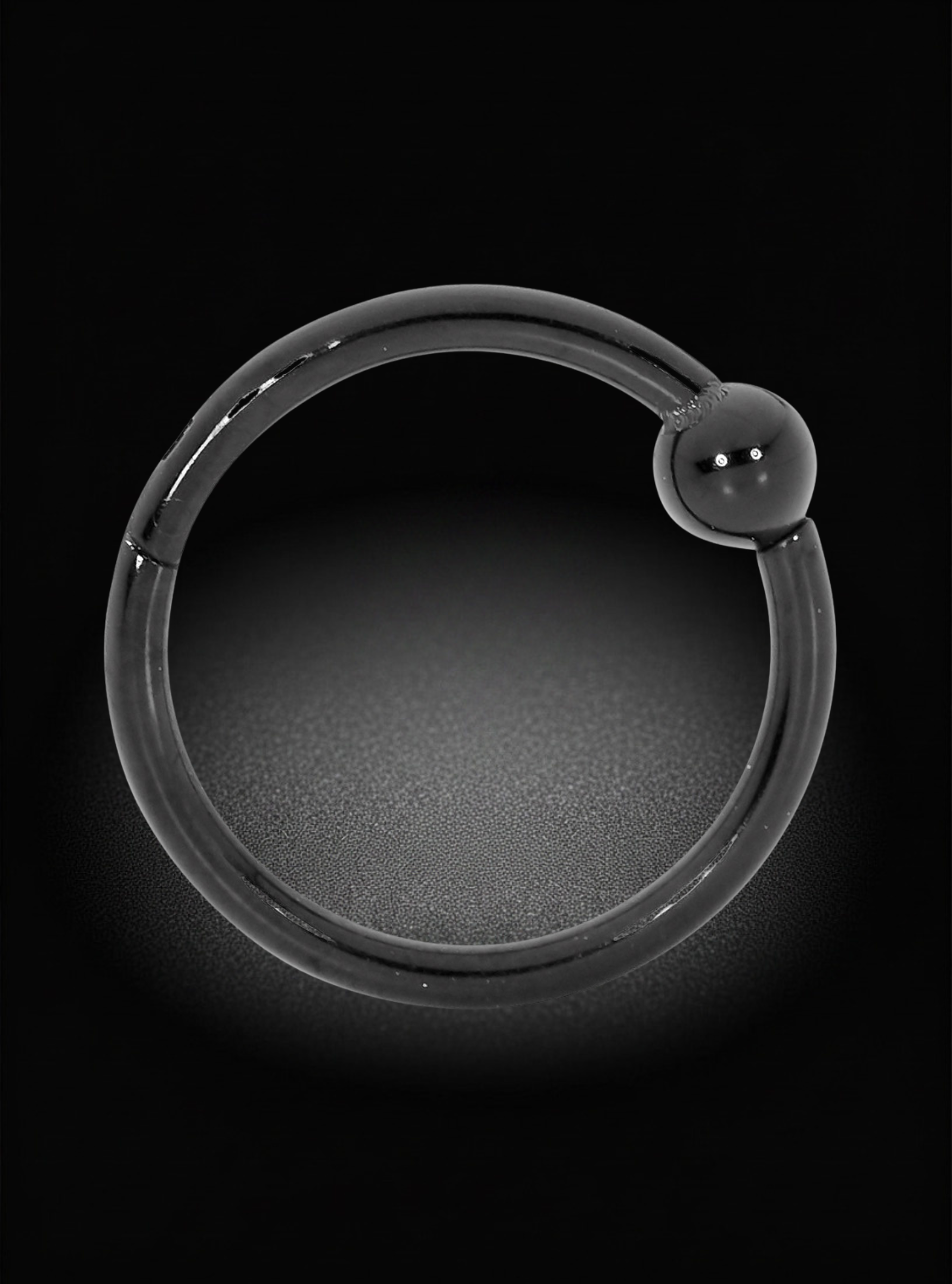A black metal hoop earring with a small, polished black bead-like accent at the outer tip, shown against a dark black background with a soft glow.