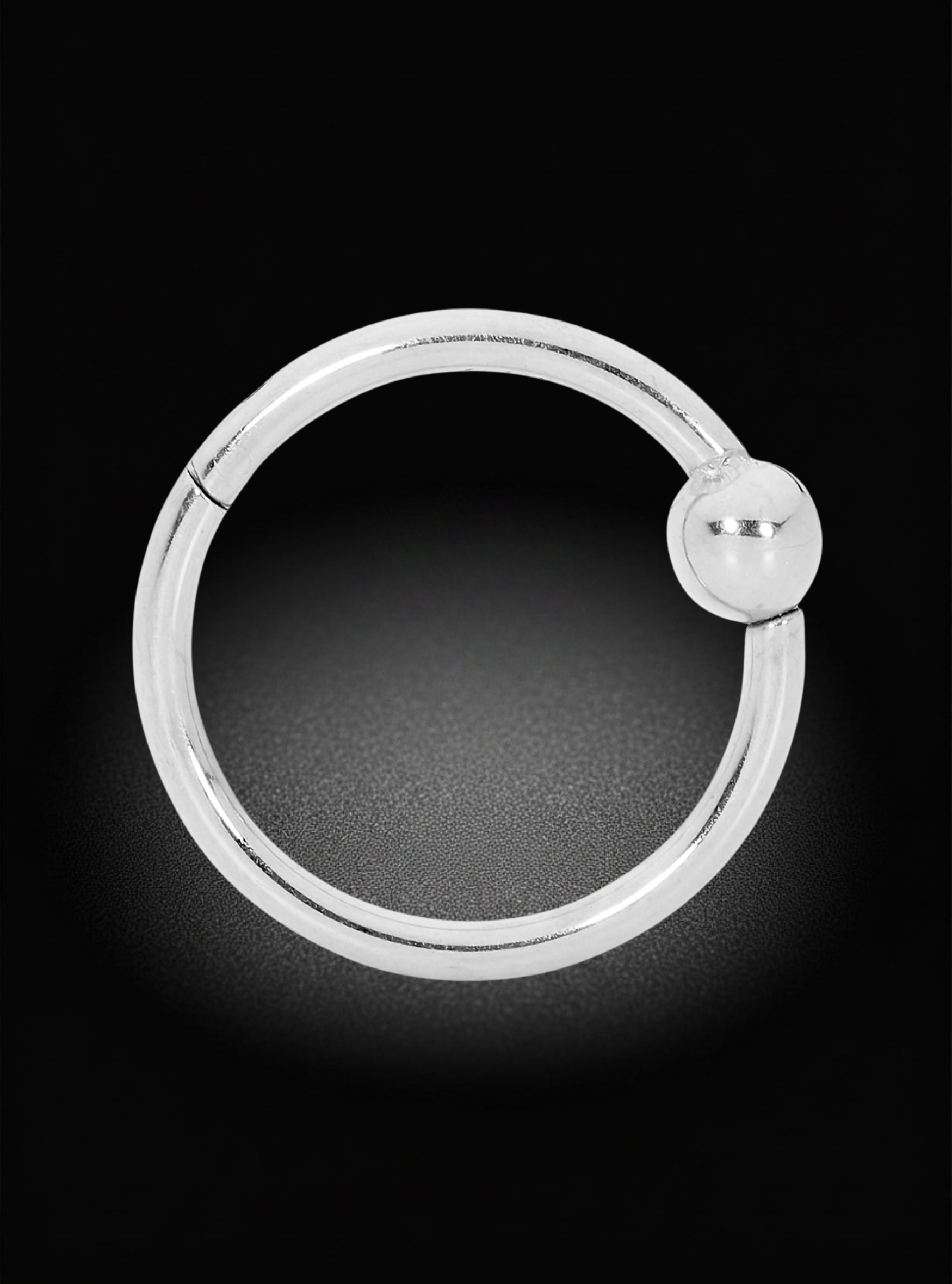 A polished silver-toned circular hoop earring with a small flat circular accent at the closure, shown on a black background.