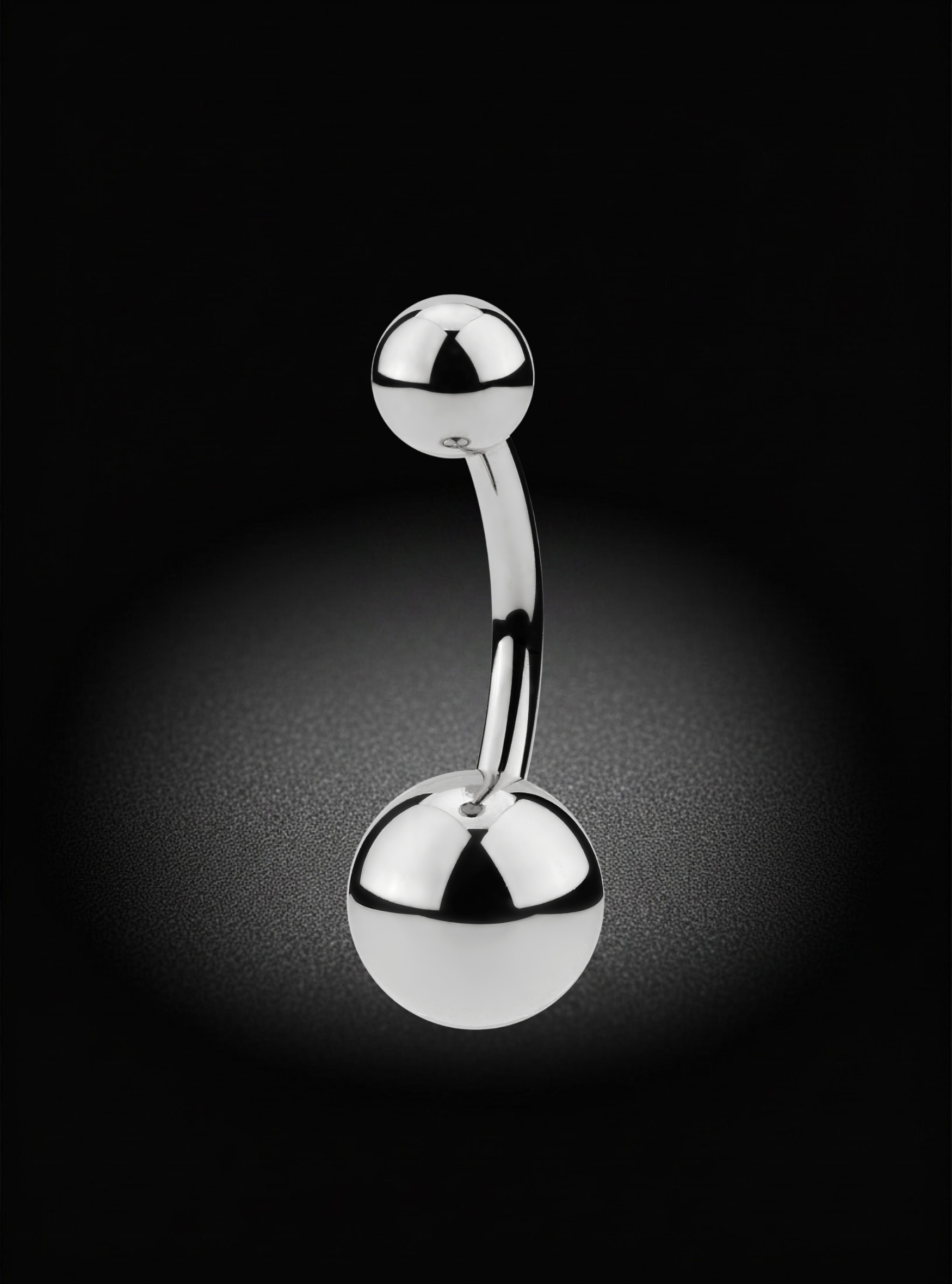 A curved barbell belly button ring with polished silver-tone ball end studs, shown on a black background with a soft spotlight effect.