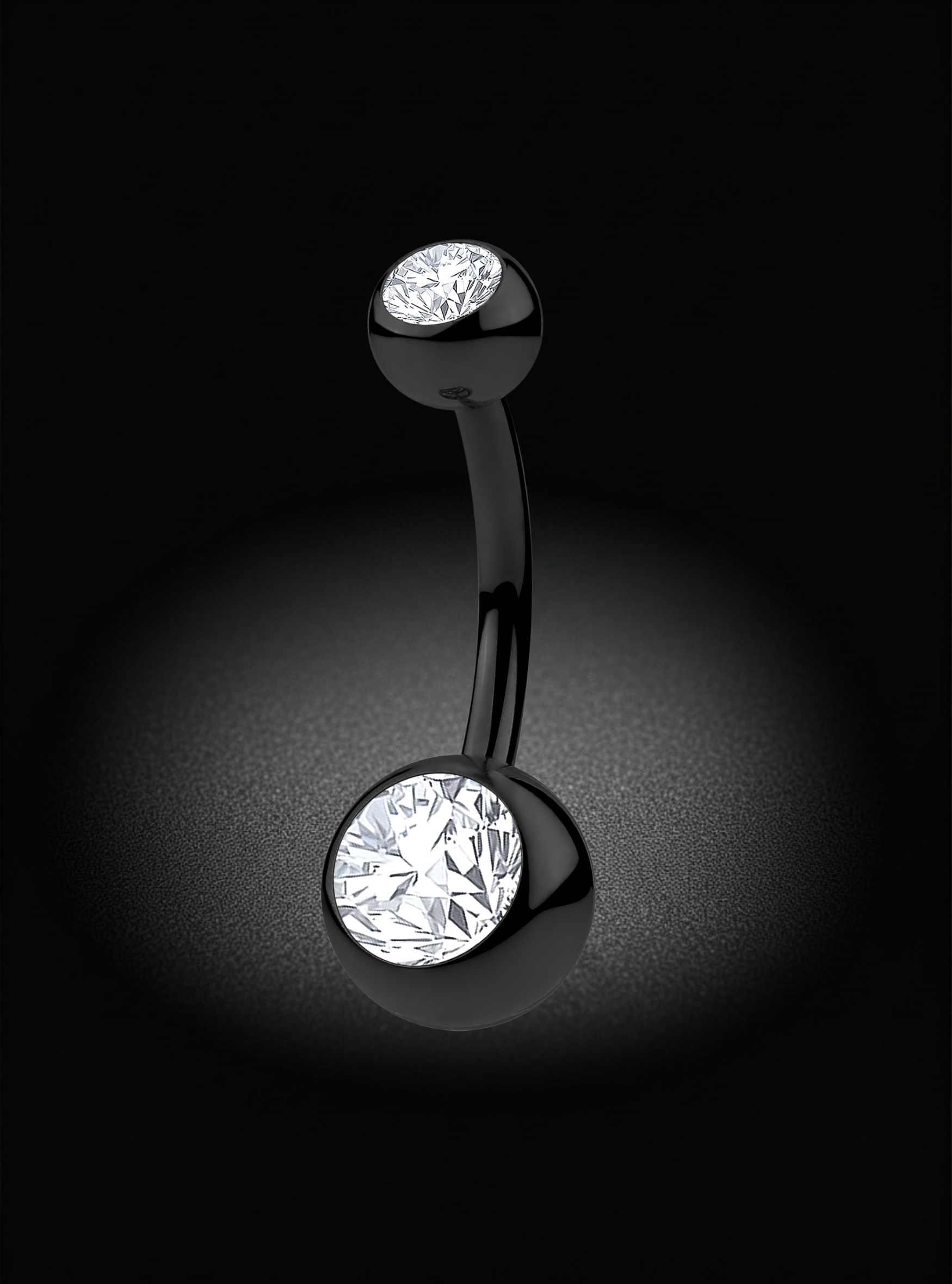A curved barbell belly button ring with a polished black metal finish and two round bezel-set clear stones, shown against a dark black background with a soft spotlight effect.