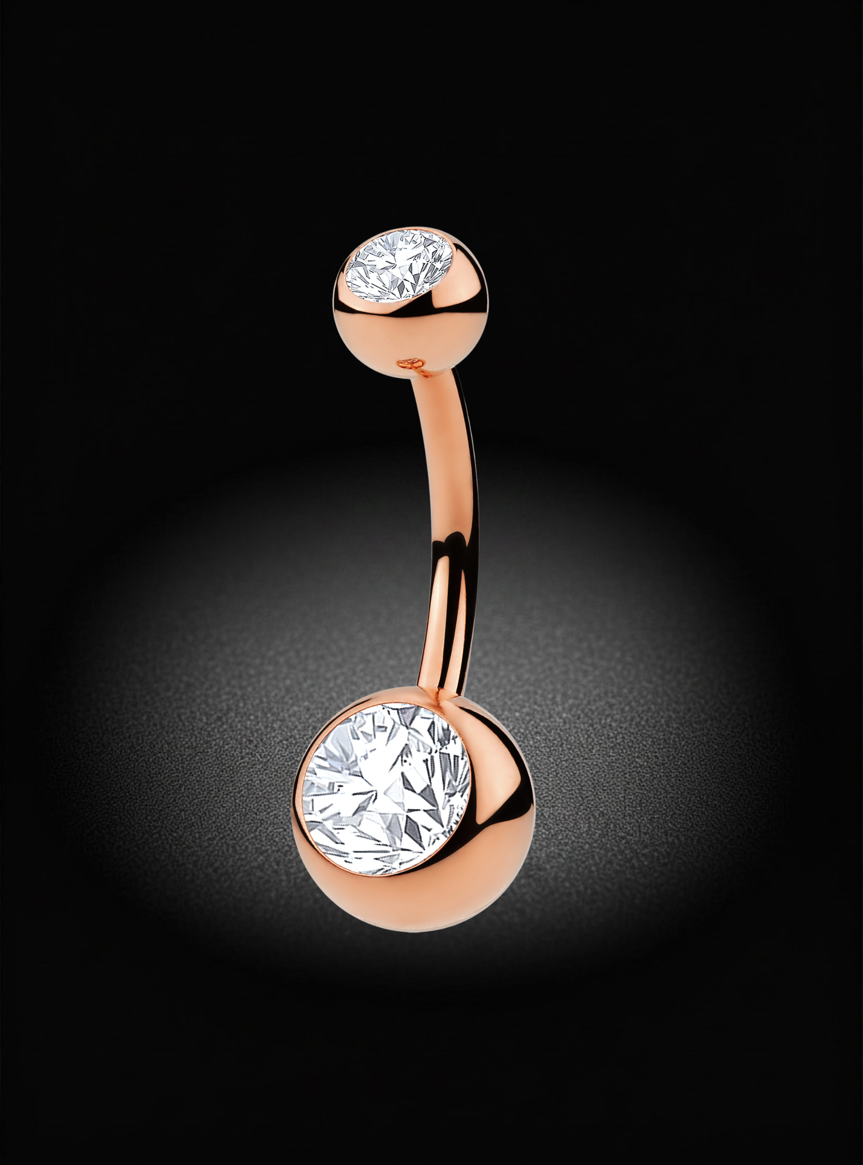 A rose gold curved barbell belly button ring with two bezel-set round clear gemstones, shown on a dark black background with a soft spotlight effect.