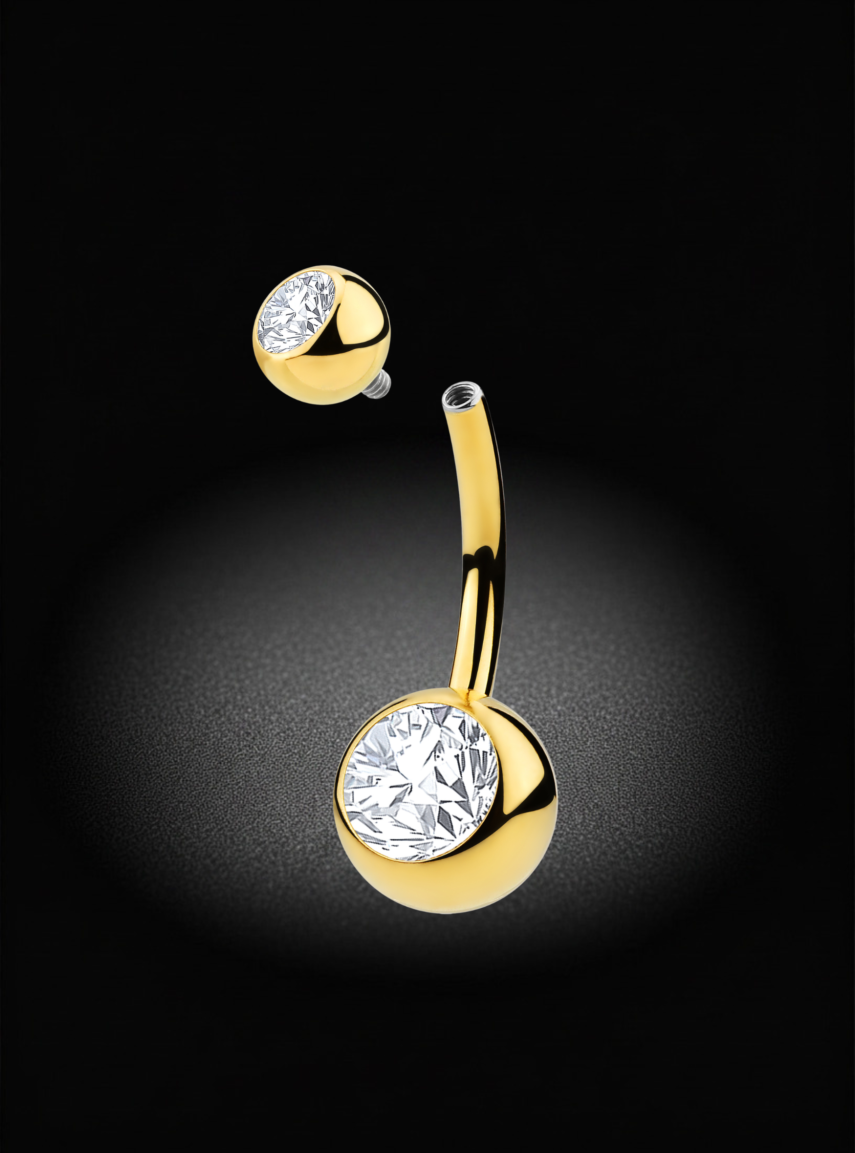 Gold curved barbell belly button piercing stud with a large round clear gemstone, shown with the matching stud detached above it on a black background.