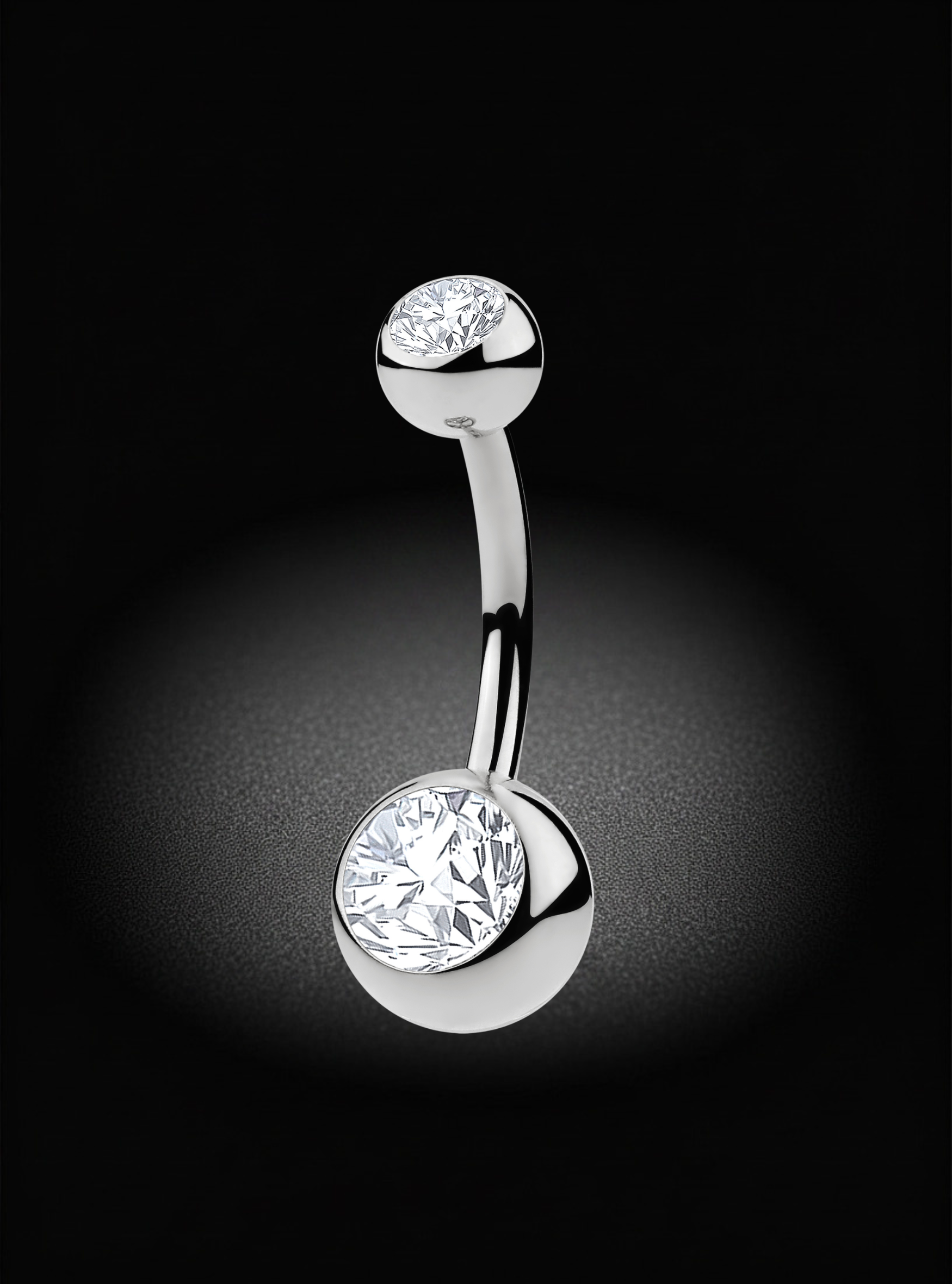 A silver-tone curved barbell belly button ring with two round bezel-set clear gemstones, shown on a black background with a soft spotlight effect.