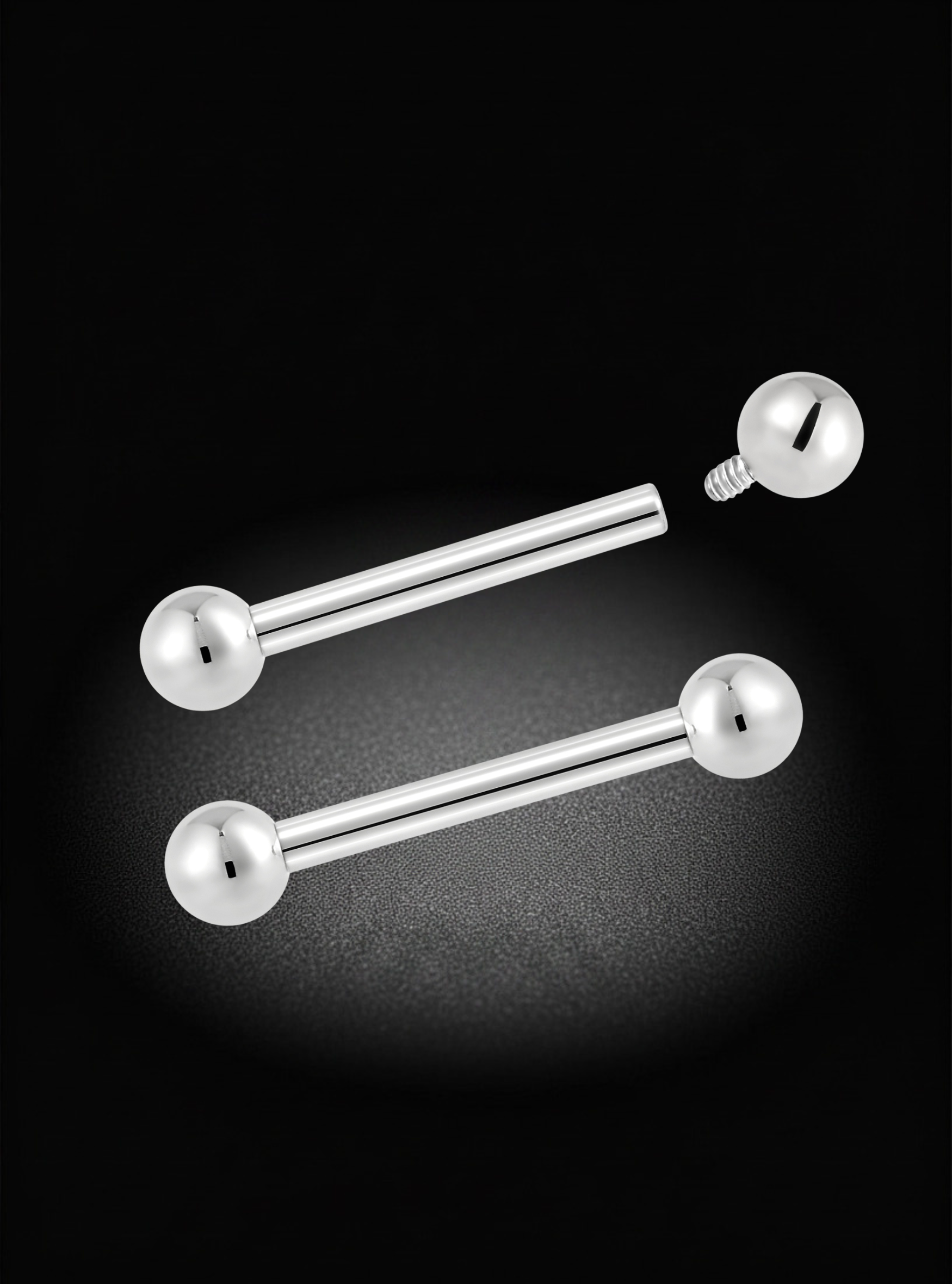 Two silver-toned barbell earrings with spherical ball ends, displayed on a black background with a soft spotlight effect.