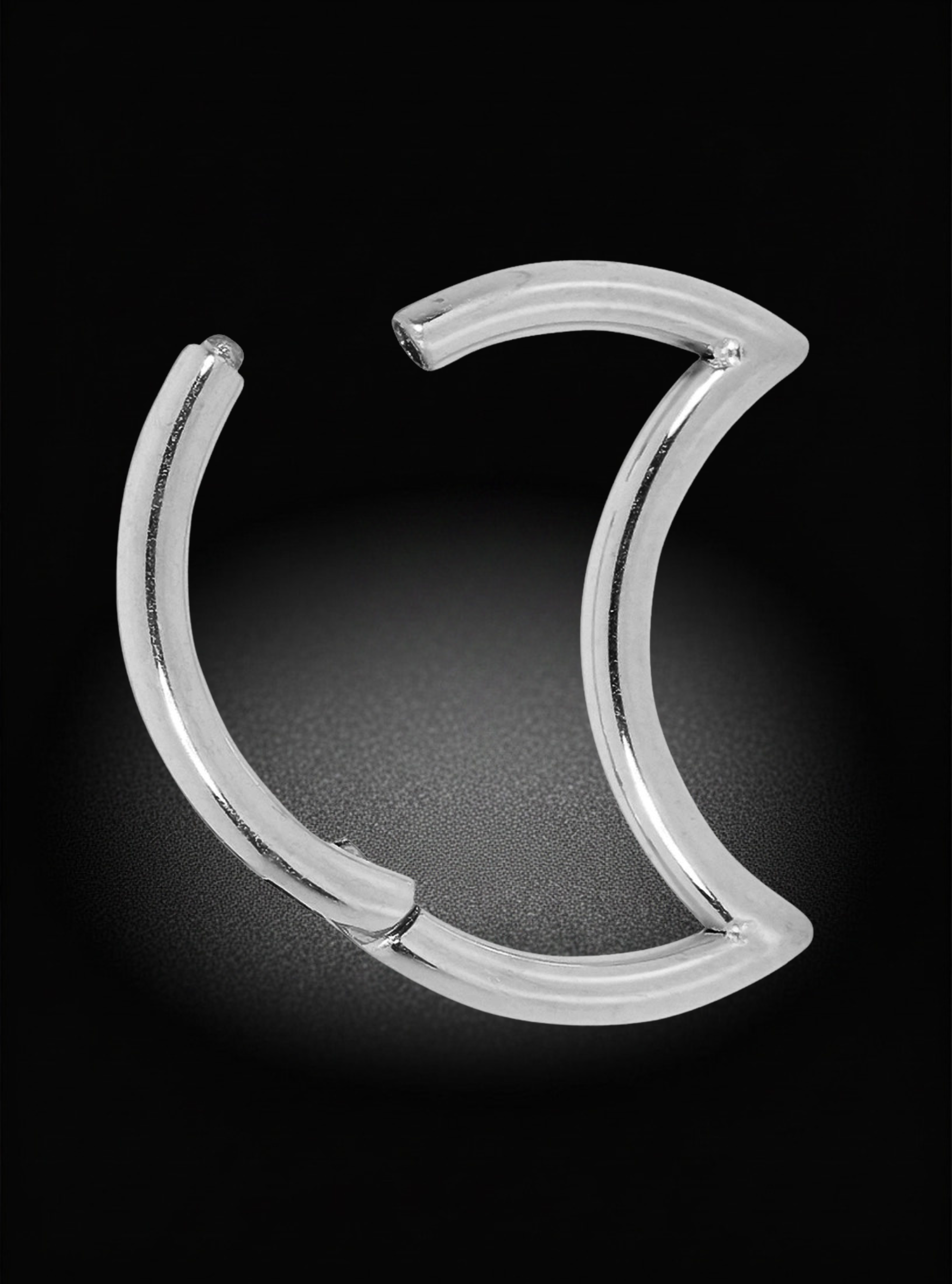 A titanium hinged segment ring curved ring, resembling a crescent moon or open C-shape, shown on a black background with a soft spotlight effect.