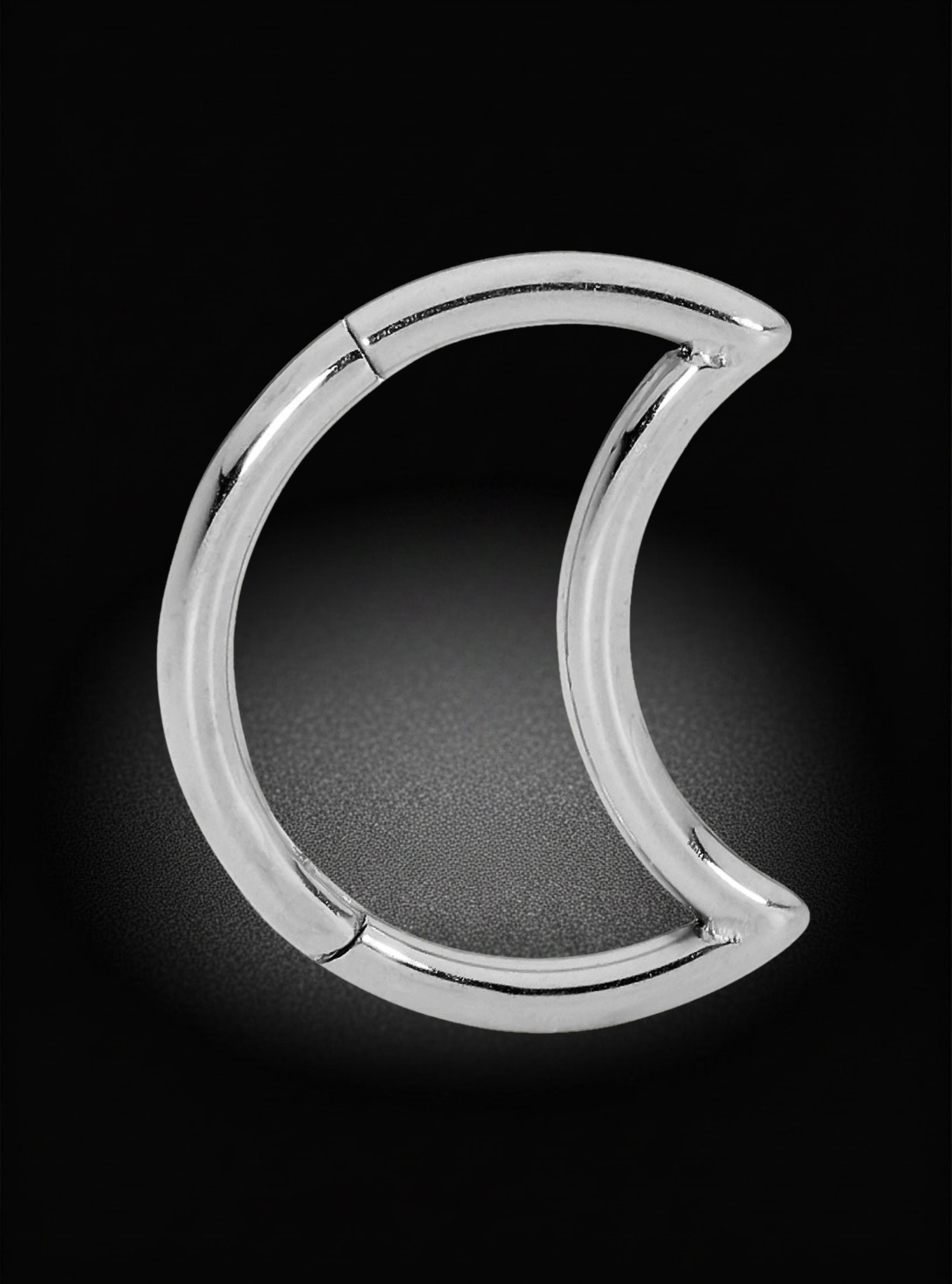 A polished silver crescent moon-shaped hoop earring, shown on a dark black background with a soft spotlight effect.