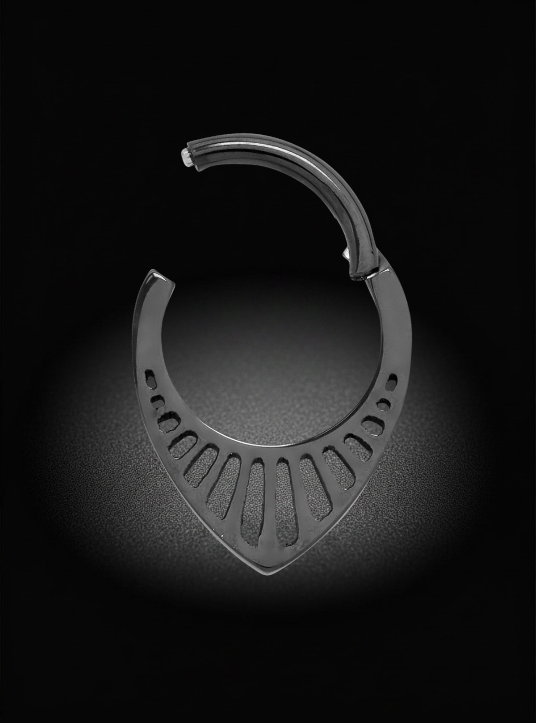 A single metallic curved body jewelry piece with a fan-like cutout pattern along the lower curve, photographed on a black background with a soft spotlight effect.