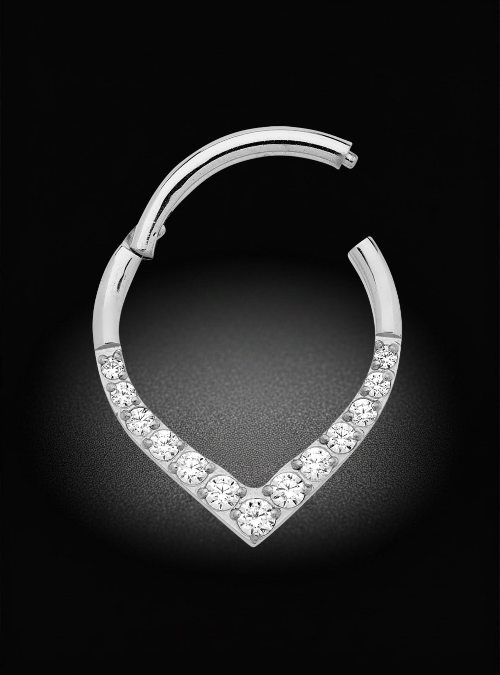 A silver-toned huggie hoop earring featuring a pavé-set row of clear round-cut stones along the lower curve, shown on a dark black background.