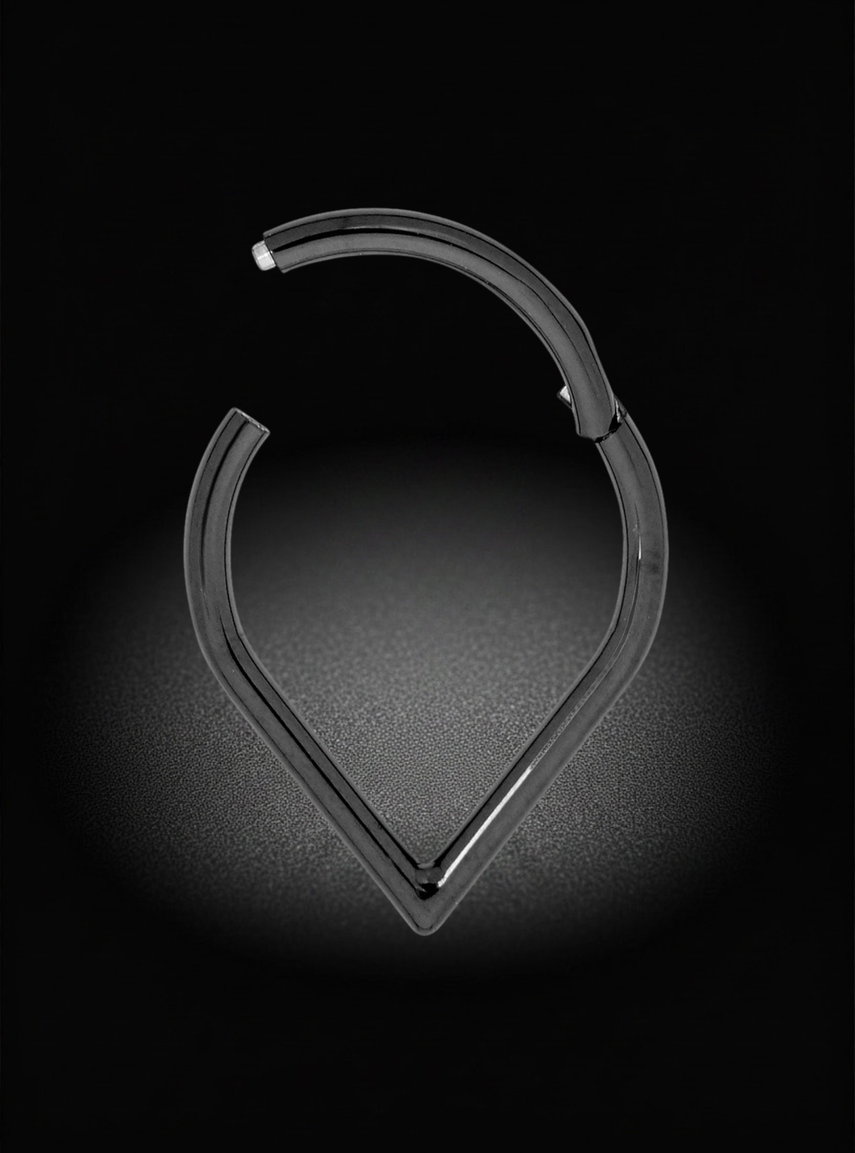 A black titanium curved ring with a triangular point, shown on a black background with a spotlight effect.