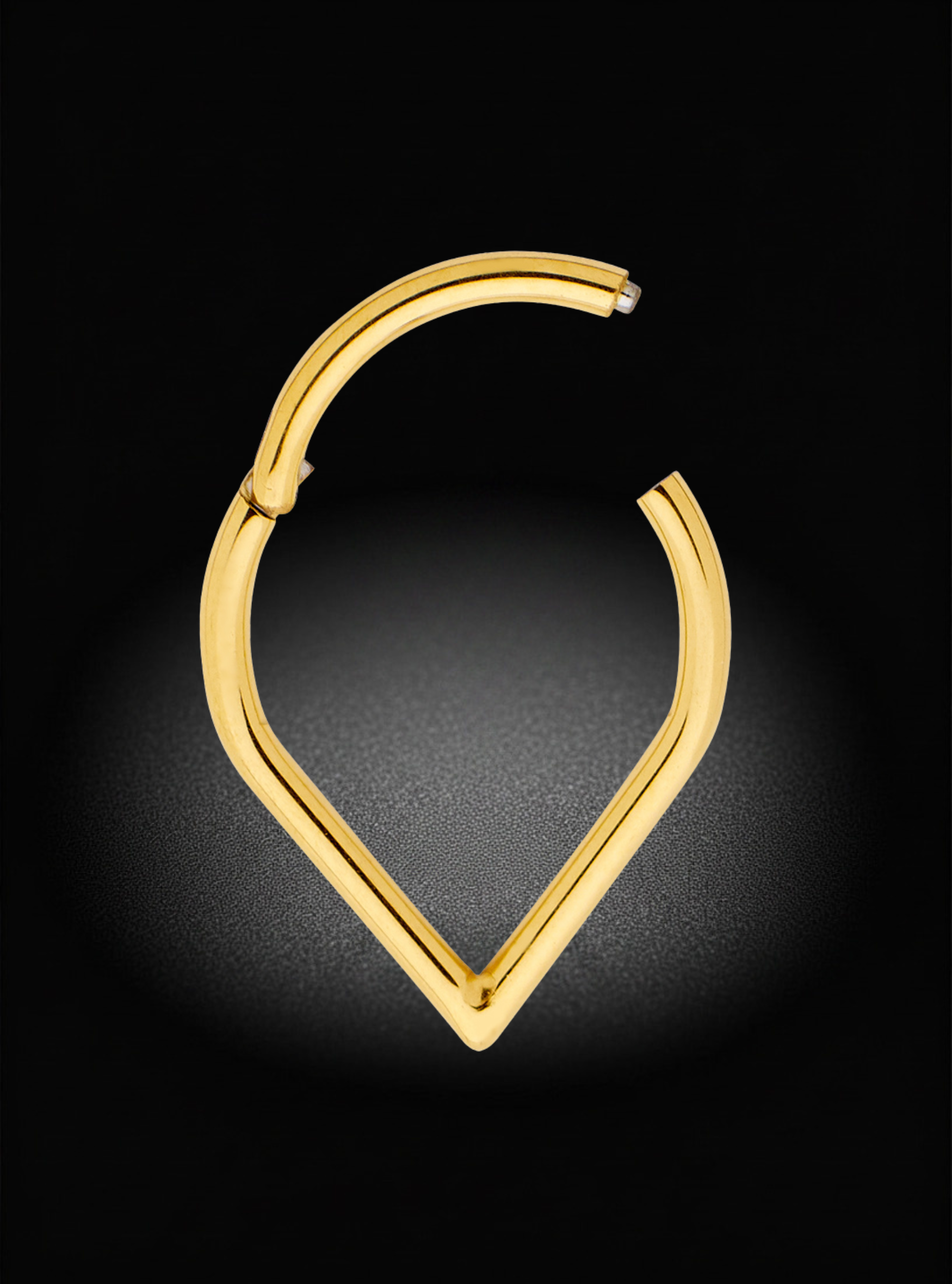 A polished gold huggie hoop earring with a unique open, curved design, shown against a dark background with a soft spotlight effect.