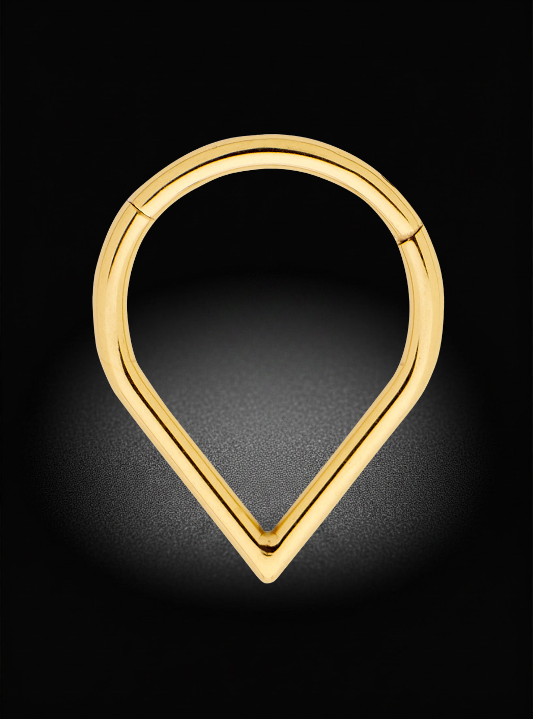 A polished gold teardrop-shaped hoop earring with a hinge clasp, shown on a dark background with a soft spotlight effect.