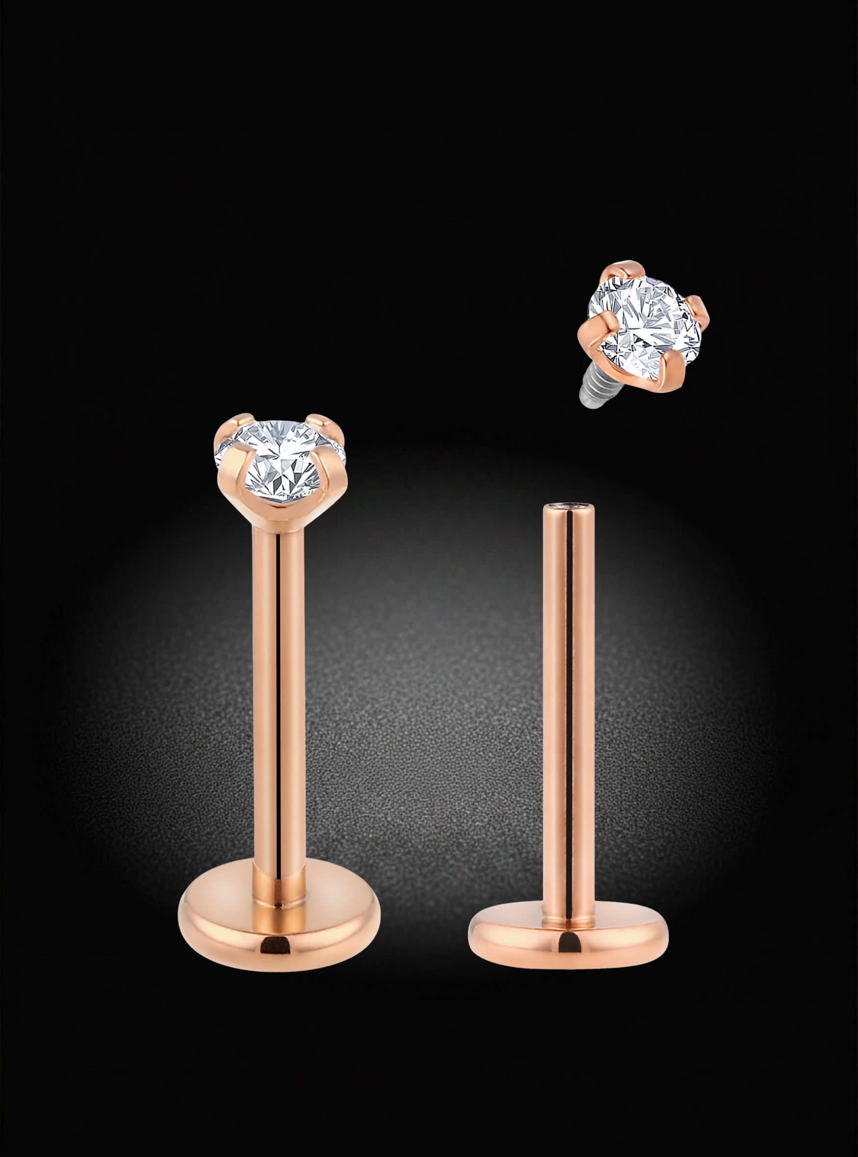 Rose gold labret piercing studs with round-cut clear gemstones, shown on a black background with one stud upright and the other floating to display the back.