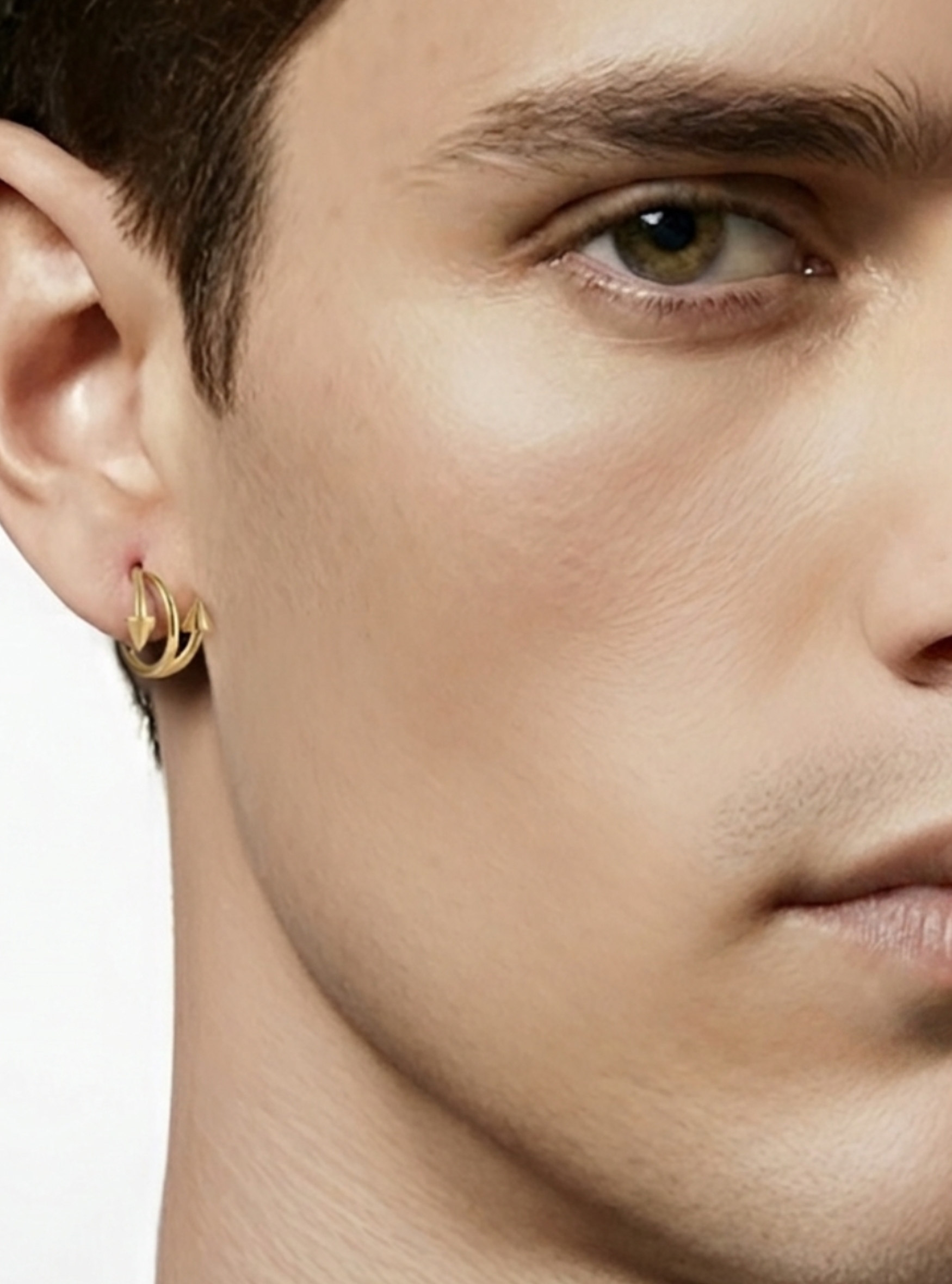 A close-up of a man's ear wearing a small gold hoop earring against a clean white background.