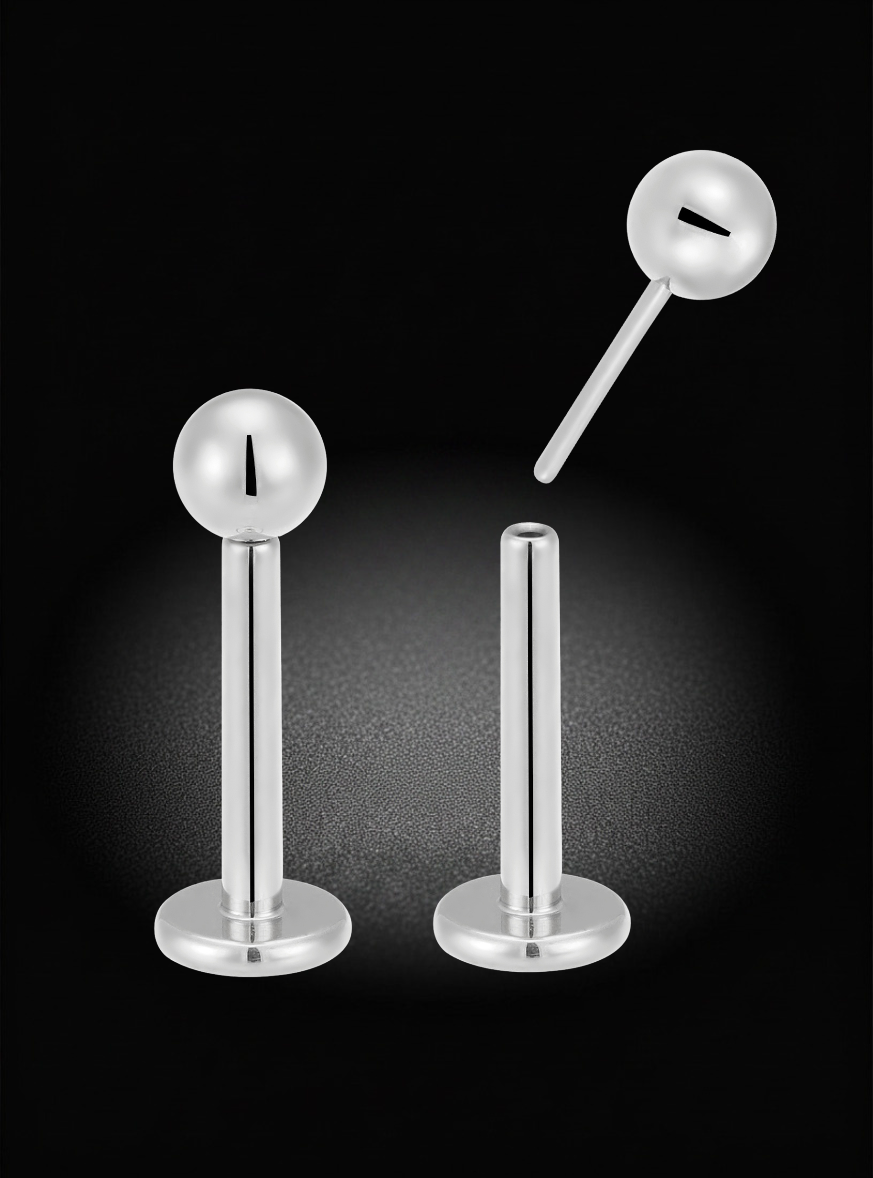 Two silver-toned labret earrings with spherical ball studs, shown on a black background with one earring upright and the other angled diagonally.