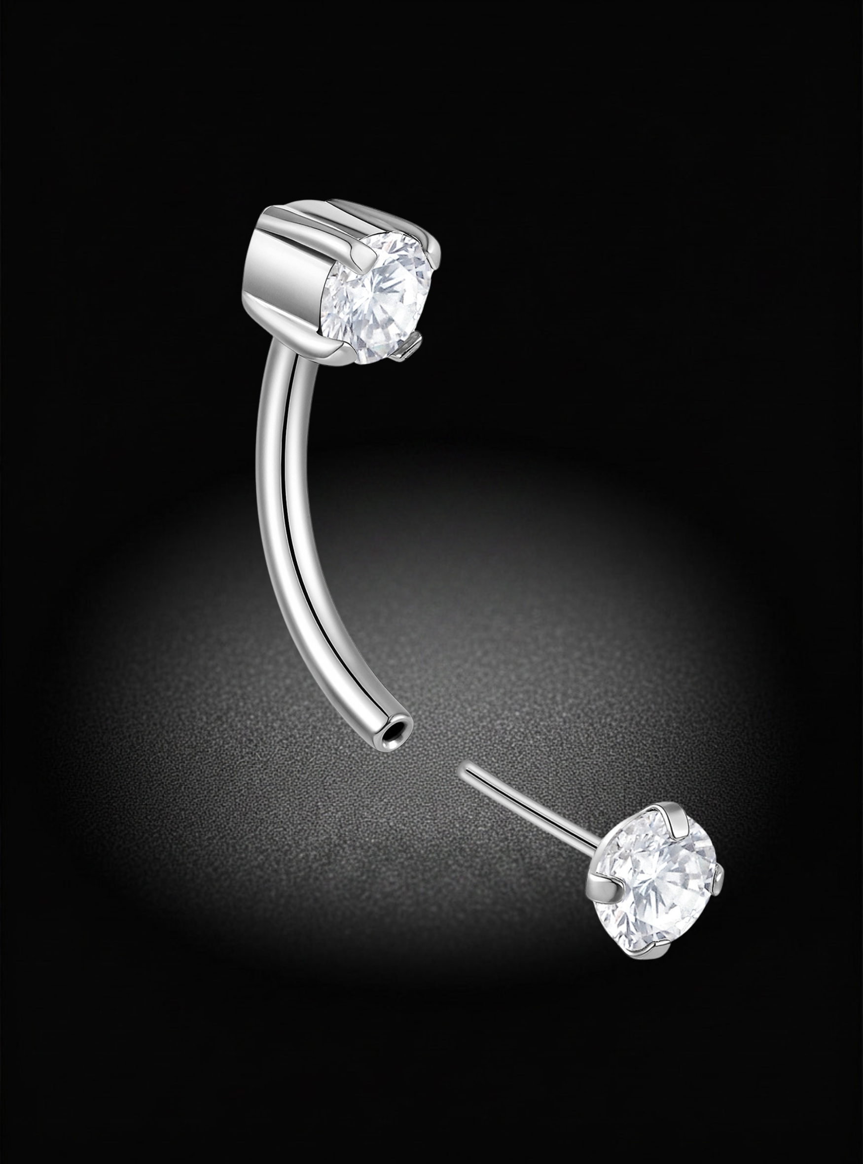 A curved barbell piercing stud earring in polished silver-tone metal with a clear round gemstone, shown alongside a matching flat-back post on a black background.