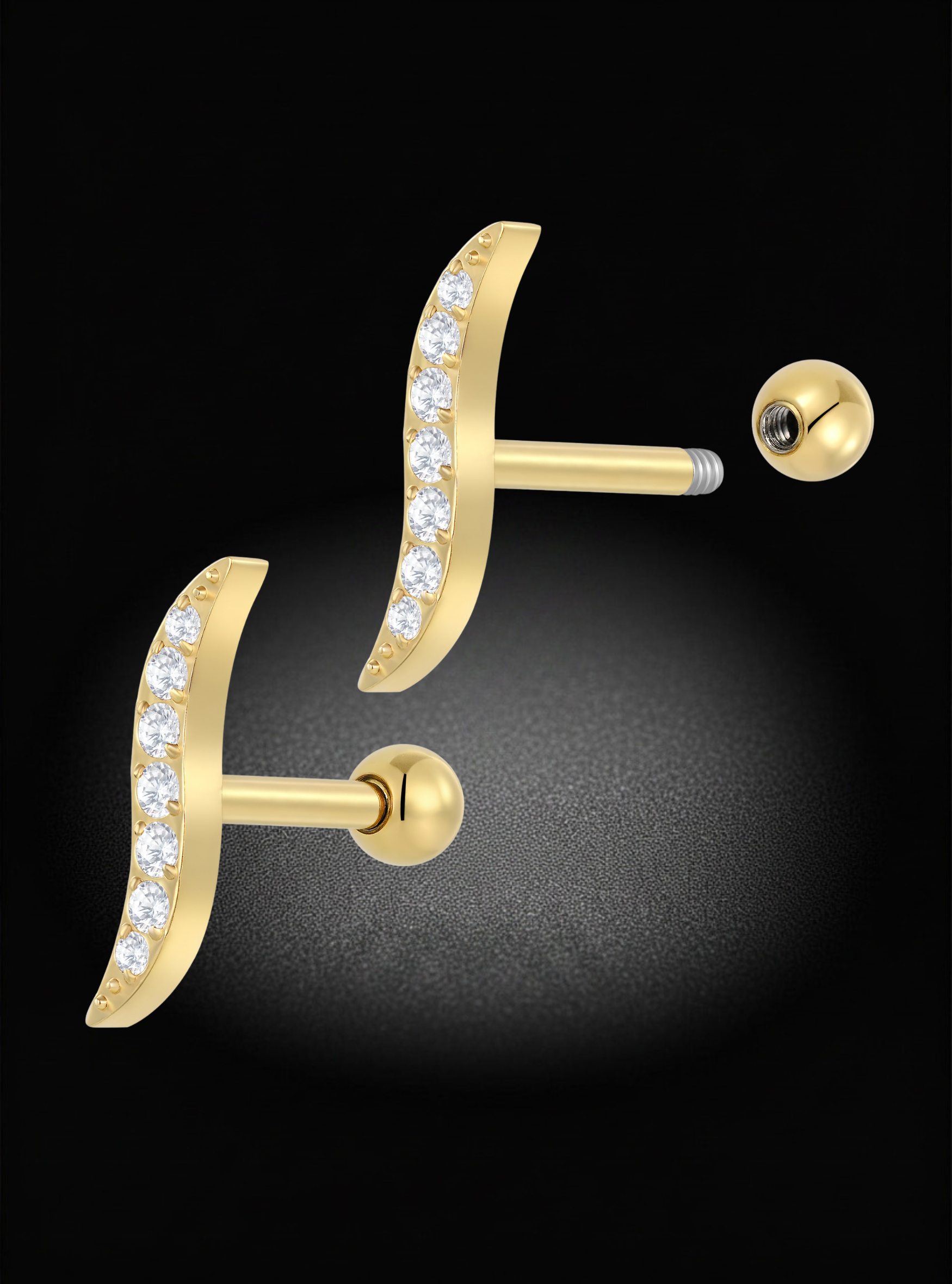 Gold crescent-shaped stud earrings with a row of clear pavé gemstones on the front, shown on a black background with one earring facing forward and the other angled to show the post and ball back.