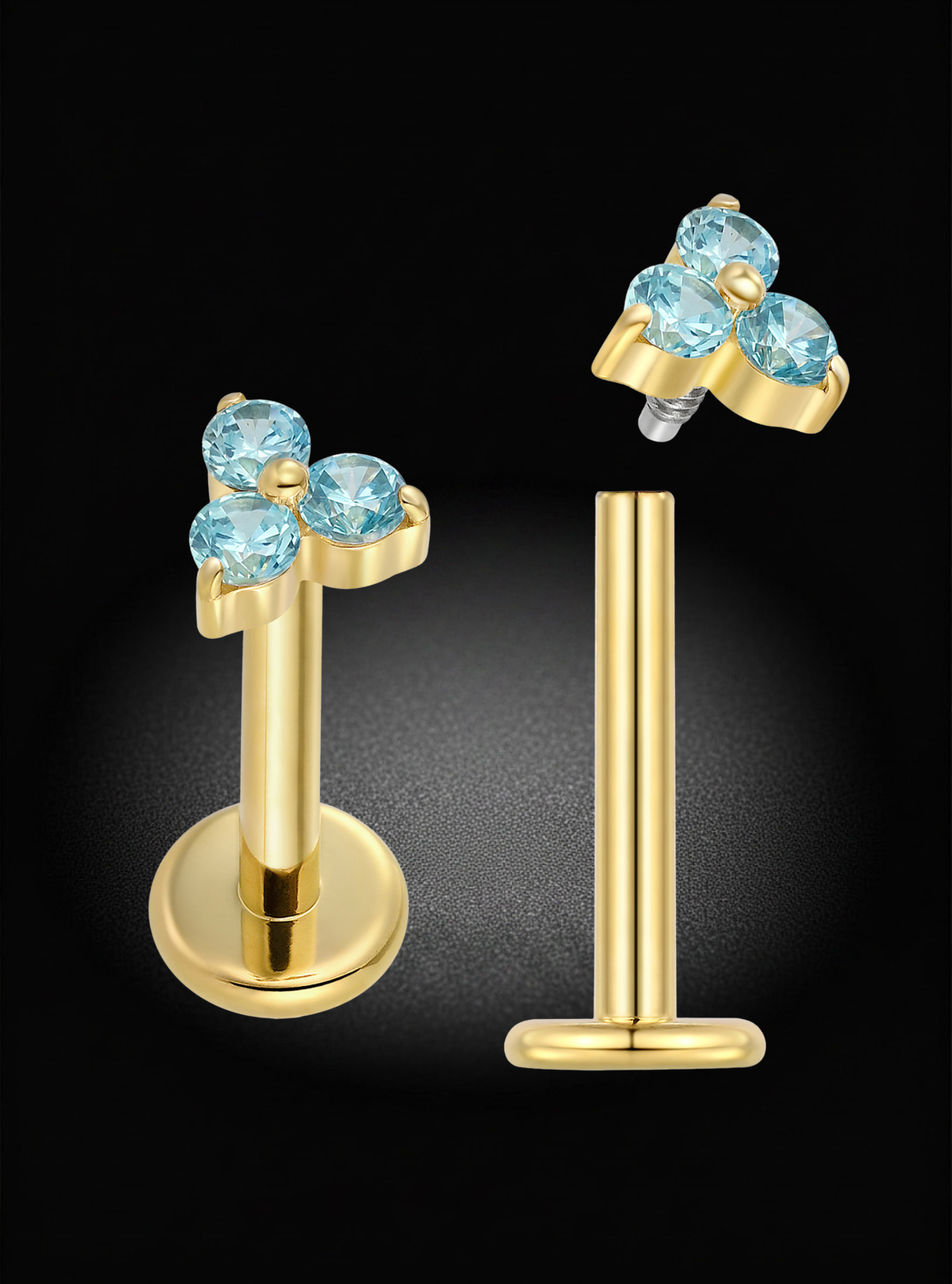 Gold body jewelry set featuring a flat-back labret and matching stud earring, both adorned with a cluster of three round-cut light blue gemstones on a black background.