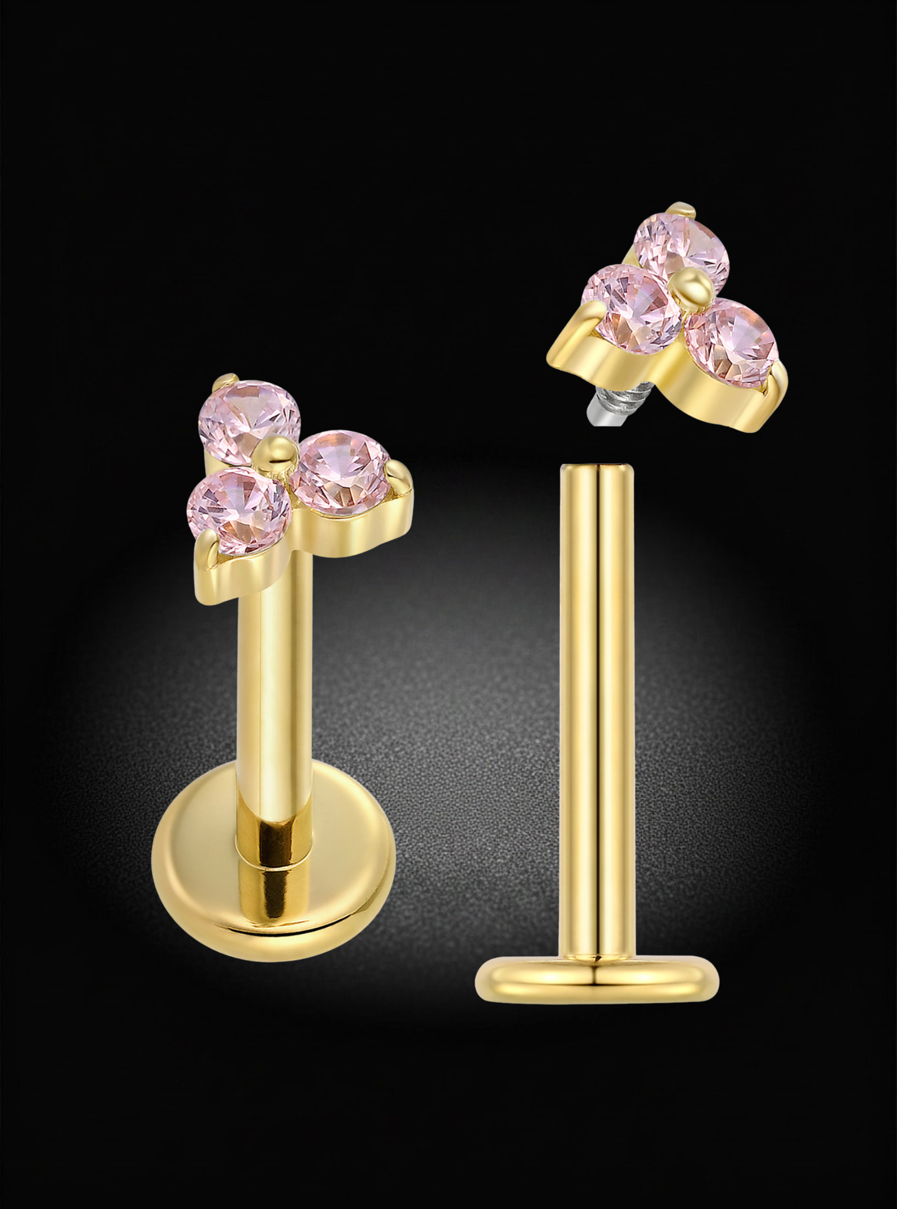 A pair of gold-colored labret stud earrings with a cluster of three round pink gemstones on the front, shown on a black background with one earring facing forward and the other angled to show the post and backing.