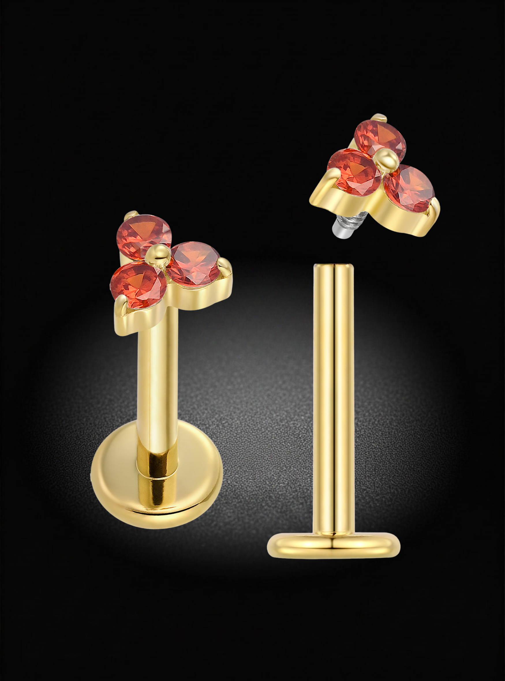 Gold-plated labret piercing stud earrings with a floral cluster setting featuring three faceted pinkish-red gemstones, shown on a black background with one earring mounted on a display stand and the other shown from the back.
