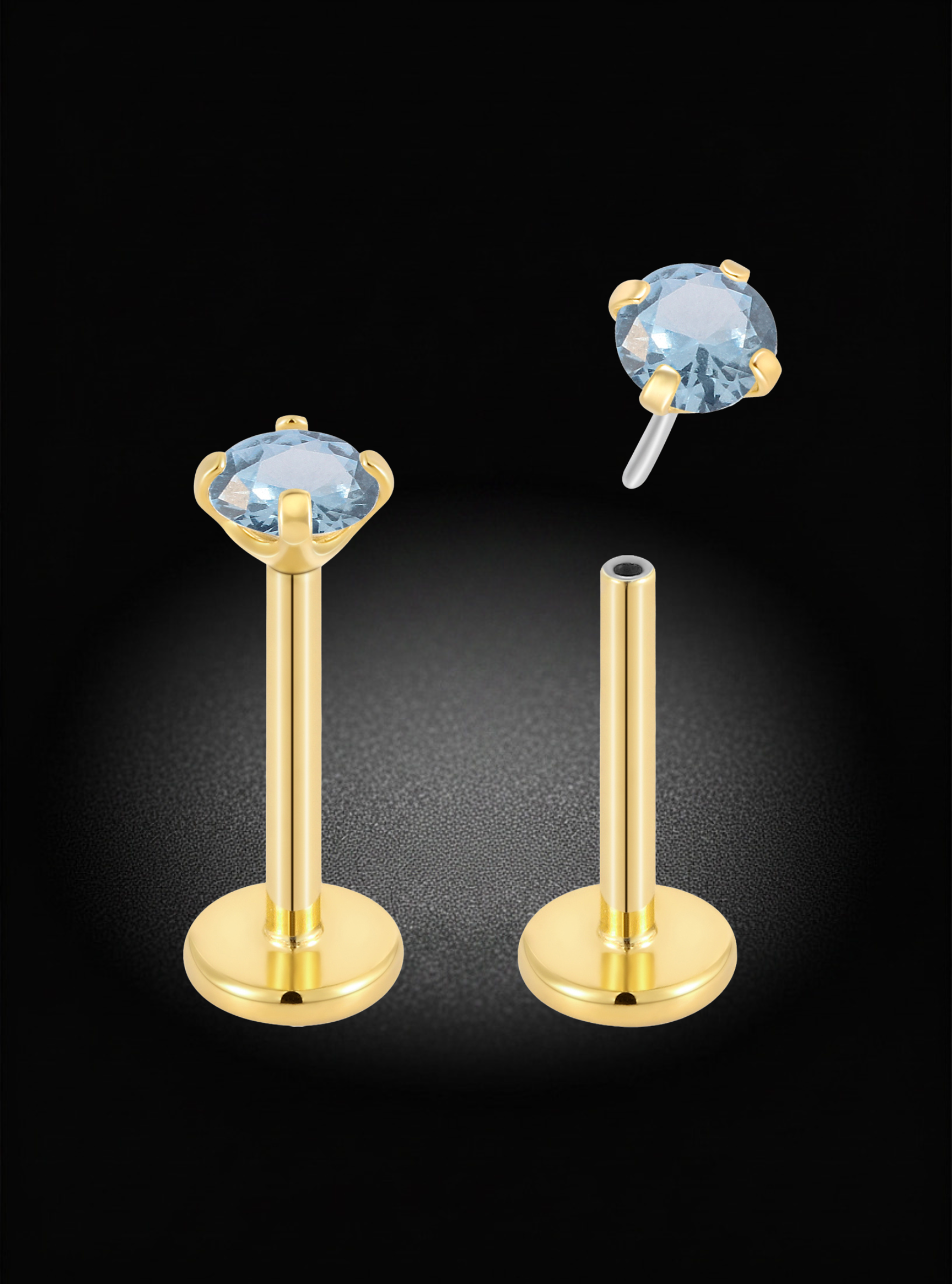 Gold labret ear piercings with oval light blue gemstones, shown on a black background with one earring assembled and the other disassembled to show the post and backing.