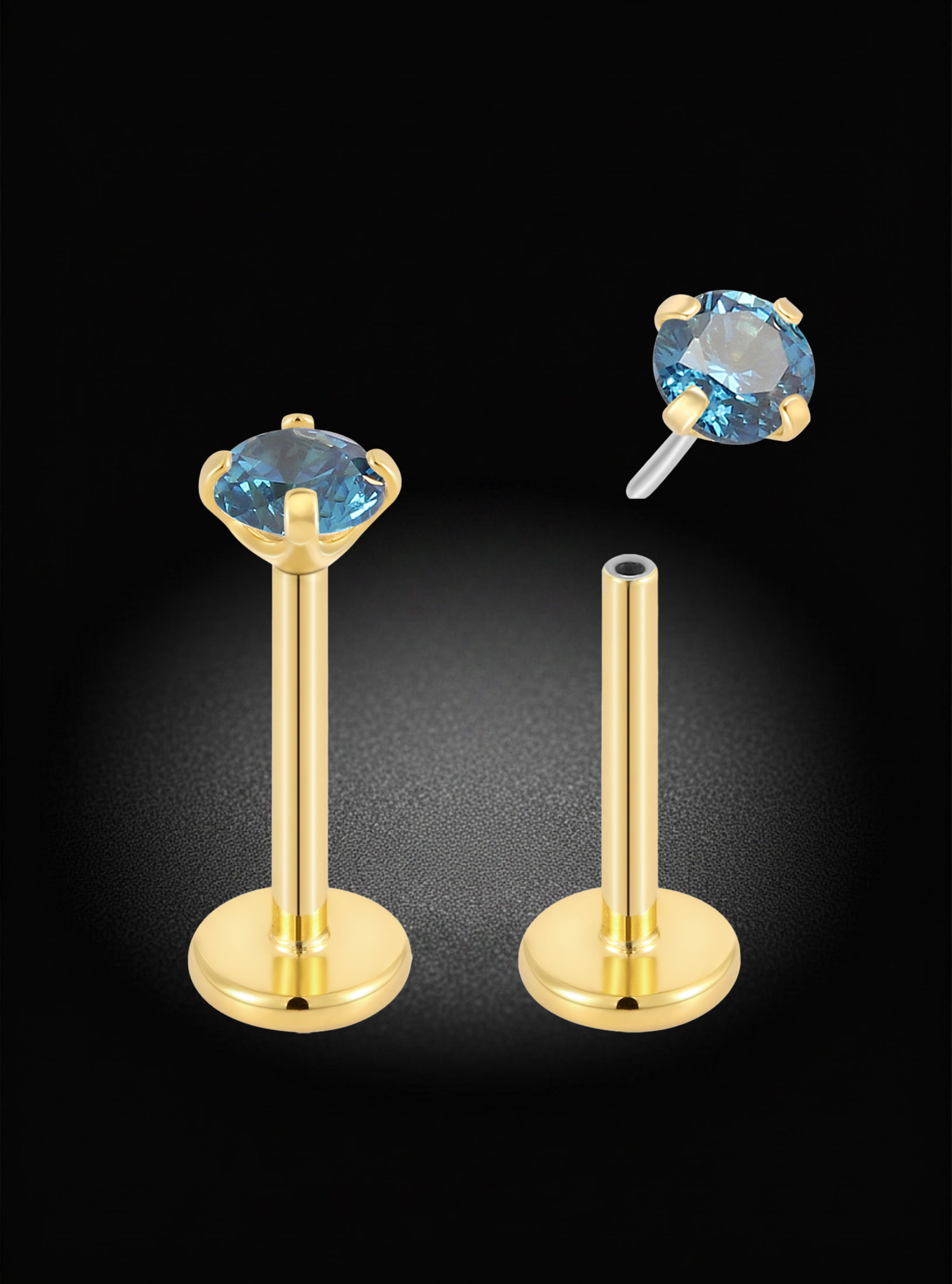 Gold labret ear piercings with oval light blue gemstones, shown on a black background with one assembled and one disassembled to demonstrate the post and flat back.