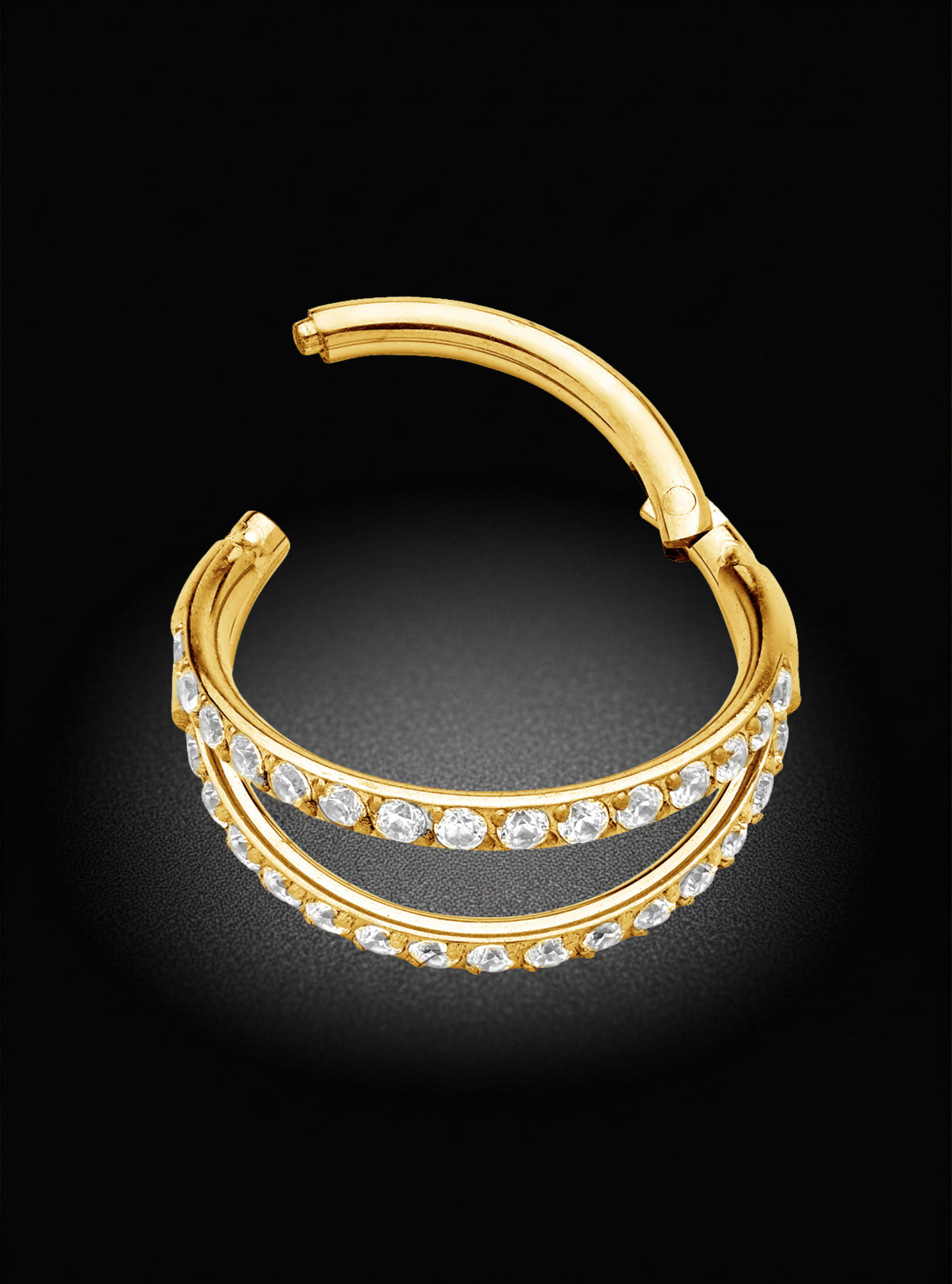 A gold-toned huggie hoop earring with two parallel rows of clear pavé-set stones, shown on a black background.