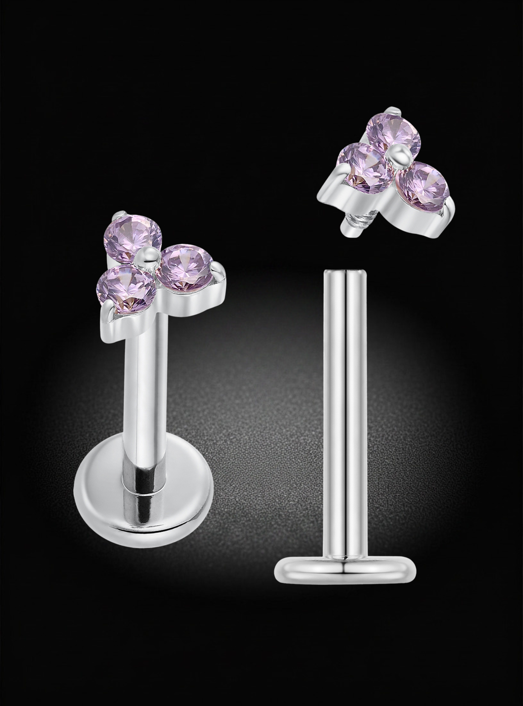 Silver-toned labret earrings with a butterfly-shaped front adorned with three light purple gemstones, shown on a black background.